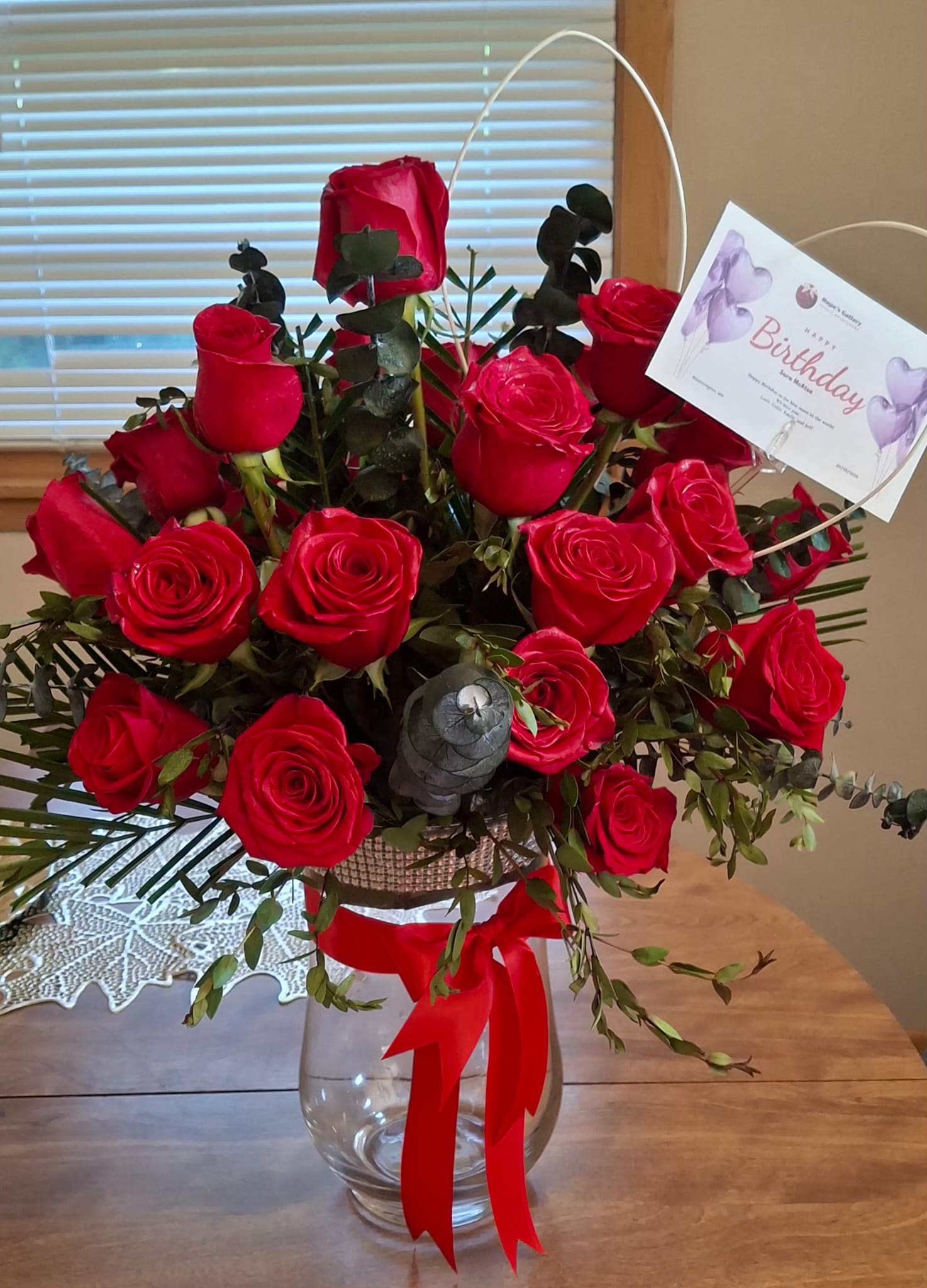 Bouquet of red roses in a clear glass vase with a birthday card