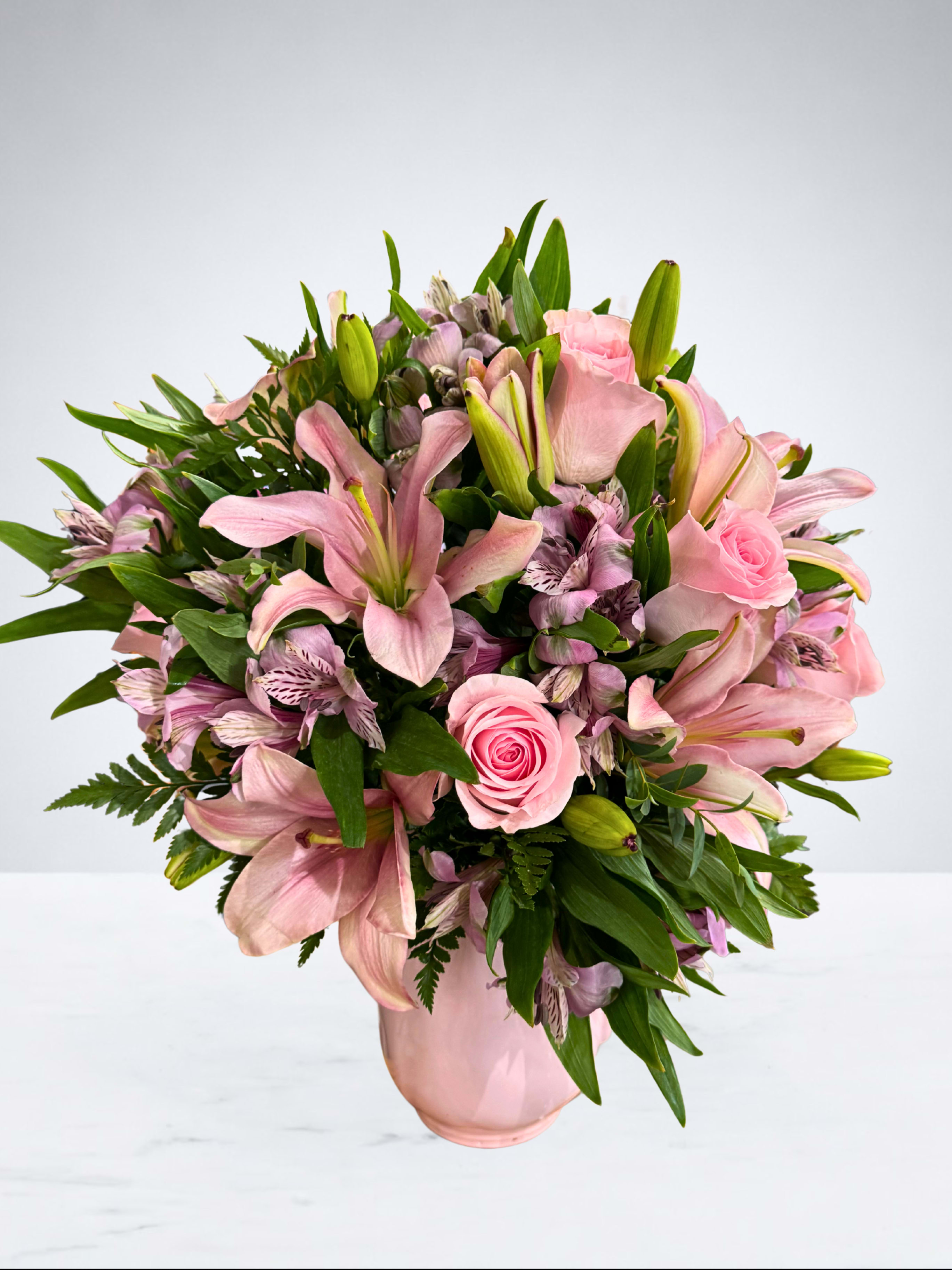 Pink lilies and roses arranged in a pink vase