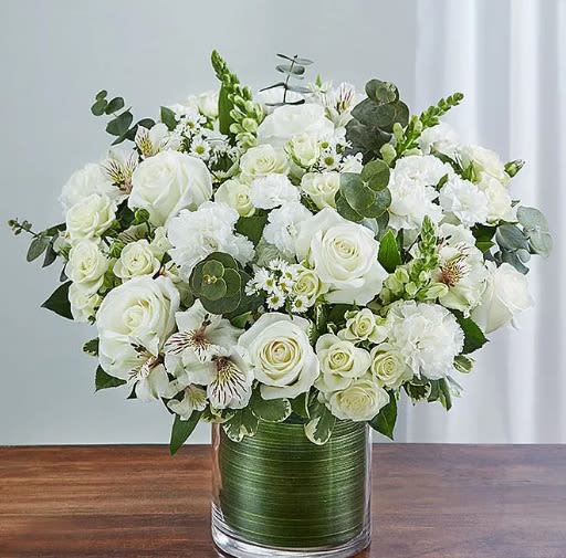 Cherished Memories - Memories are timeless treasures of the heart, meant to be cherished. Our striking, all-white sympathy arrangement of roses, snapdragons, alstroemeria and more, elegantly designed by hand in a graceful cylinder vase, is a touching tribute to a life well lived and the memories that will be held dear forever. Arrangement of white roses, spray roses, snapdragons, alstroemeria, carnations, mini carnations and monte casino; accented with fresh greenery.