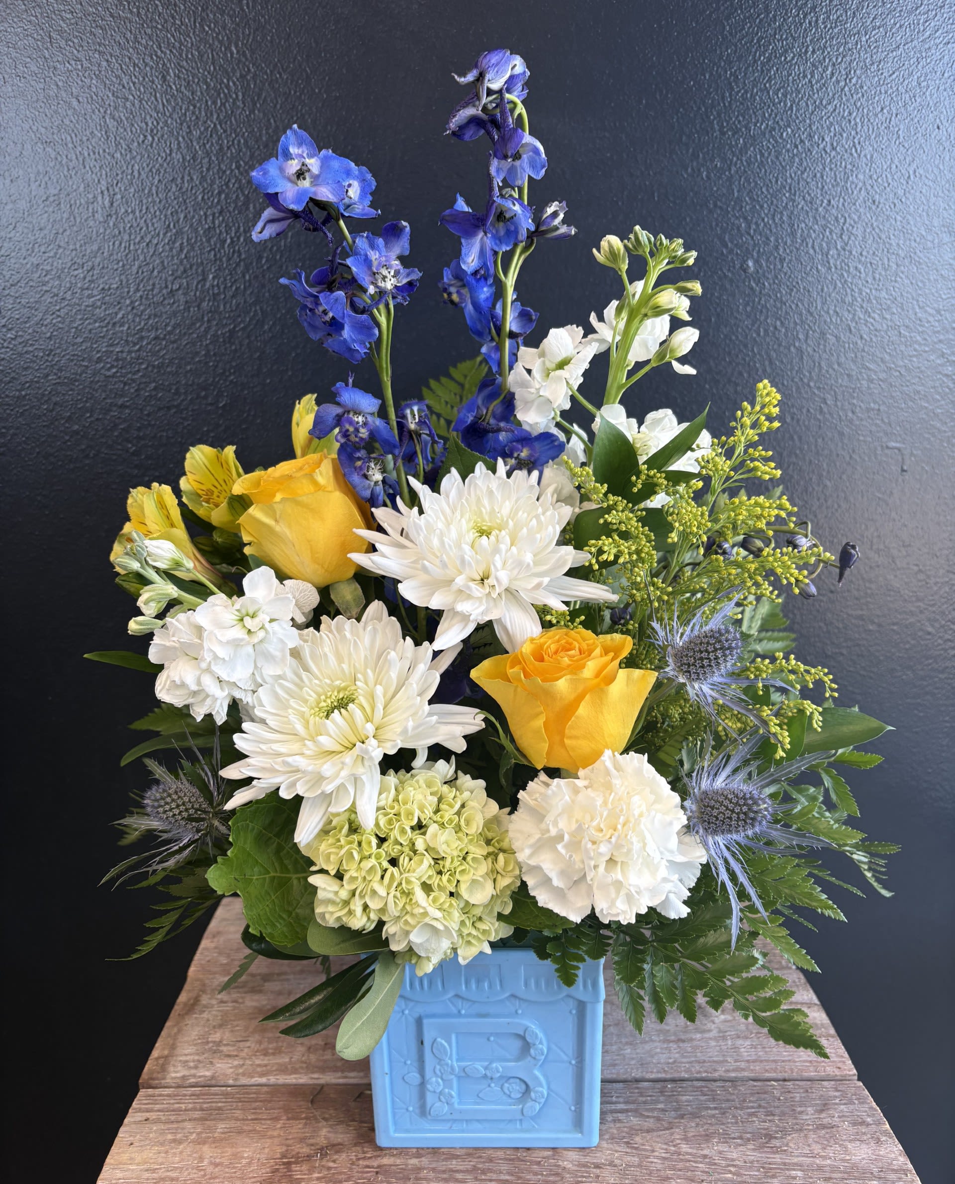 Bundle of Joy  - This charming baby arrangement features soft, cheerful blooms nestled inside a classic ABC block container, symbolizing the joy of new beginnings. Gentle colors and playful details create a sweet, welcoming display perfect for celebrating a new arrival. Let us know boy or girl!