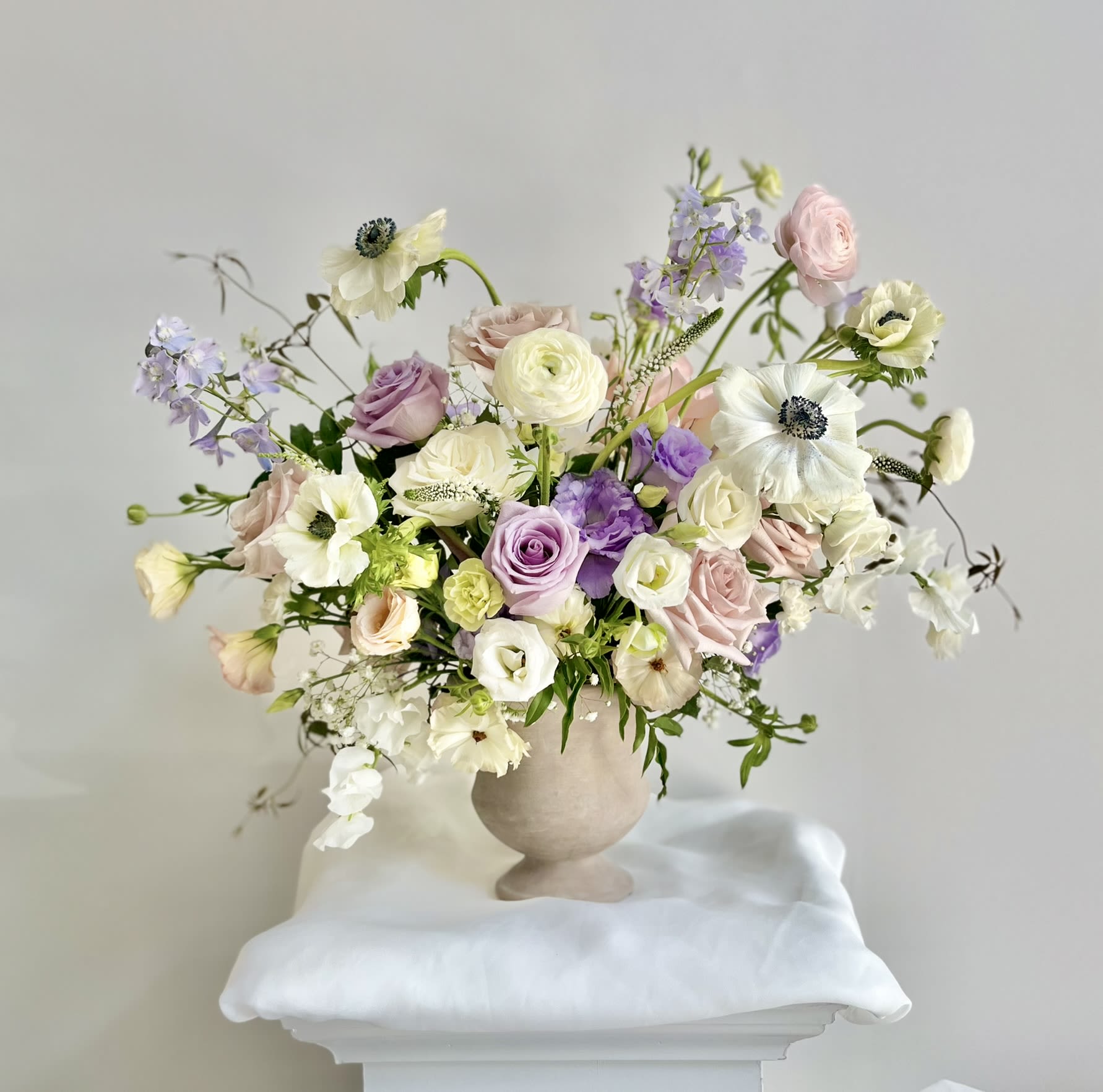 Purple Blush Center Piece (front side) - Premium 360 degree all-round arrangement with a deluxe size pedestal vase. Decorated with pastel anemones, roses, lisianthus, ranunculus and delphinium - airy, garden-style centerpiece.  Perfect for gift giving and brightening up your work place!