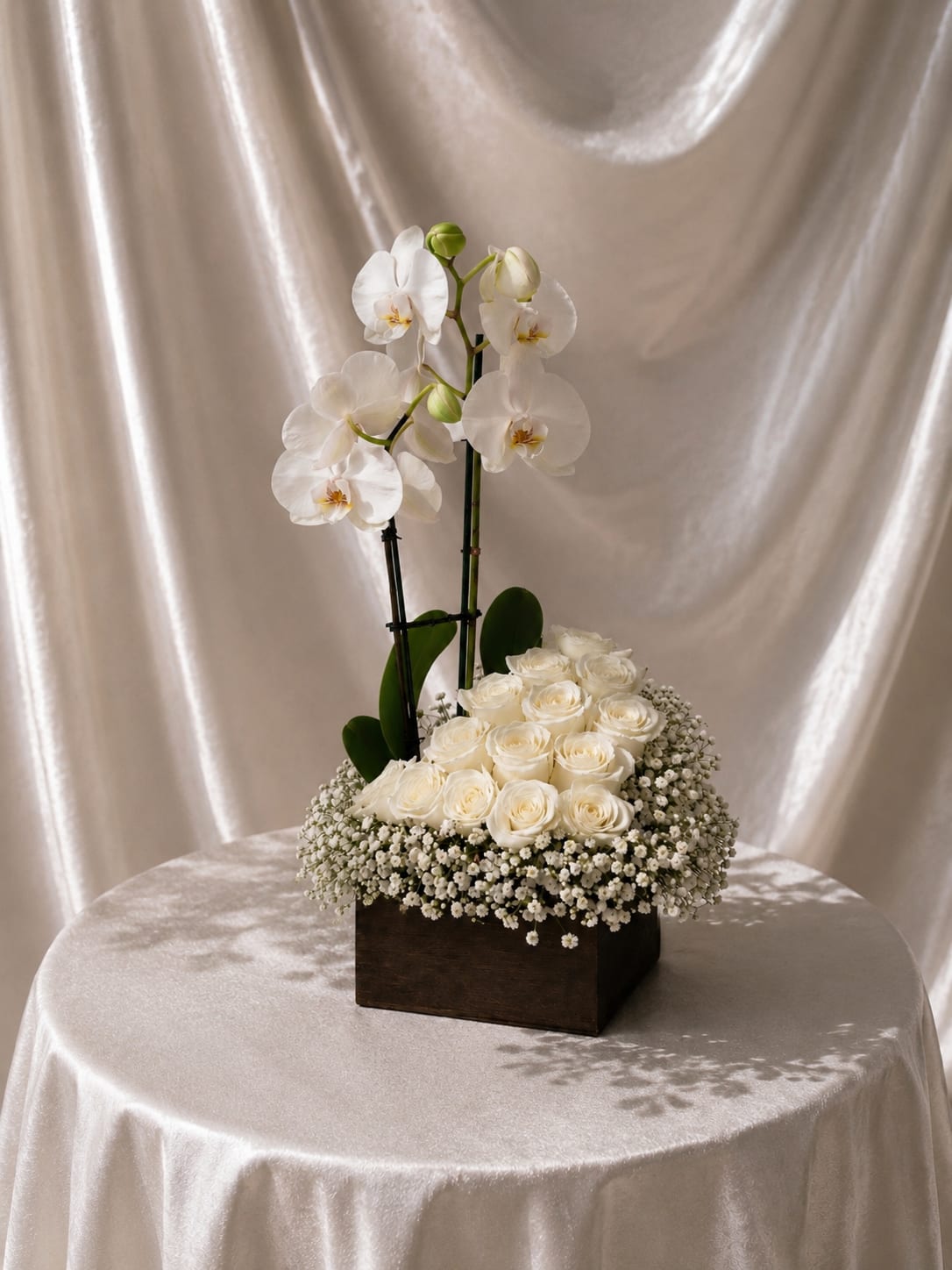 Elegant White Roses &amp; Orchid Arrangement in Wooden Box - A timeless and elegant floral arrangement featuring premium white roses paired with a stunning orchid, beautifully designed in a modern rectangular wooden box base and accented with delicate baby’s breath.  This sophisticated design combines the purity of white roses with the graceful height and structure of orchids, creating a refined and luxurious presentation. The soft textures and clean color palette make this arrangement perfect for both modern and classic settings. Vase color may be changed depending on availability.  Better for:  Mother’s Day, sympathy, get well, thank you, birthdays, anniversaries, or elegant home décor.