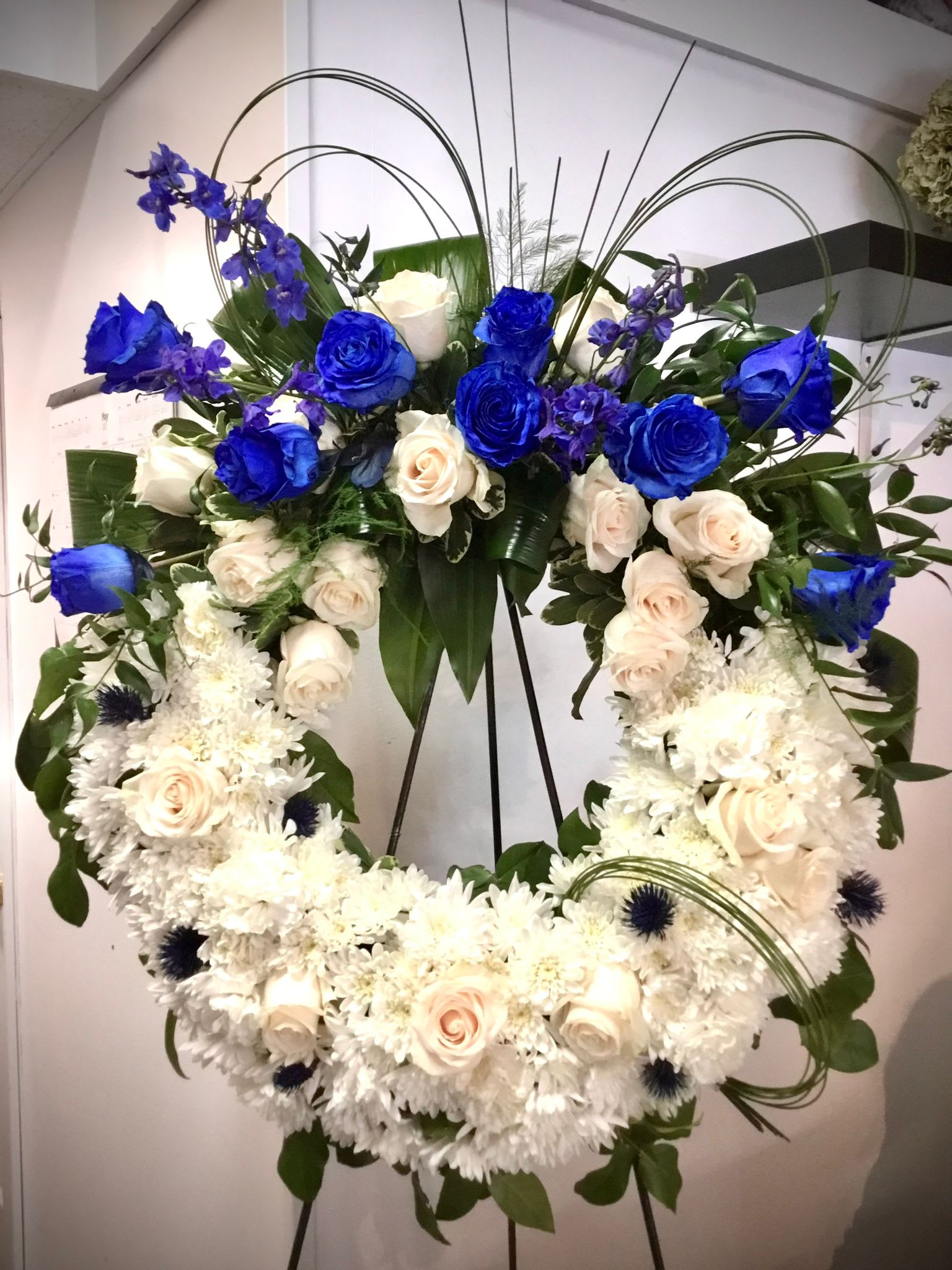 Large heart-shaped floral wreath with blue and white roses