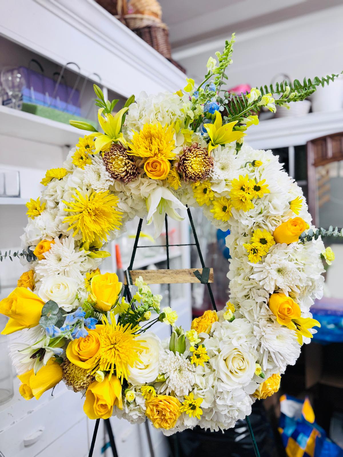 Yellow and white floral wreath on a stand