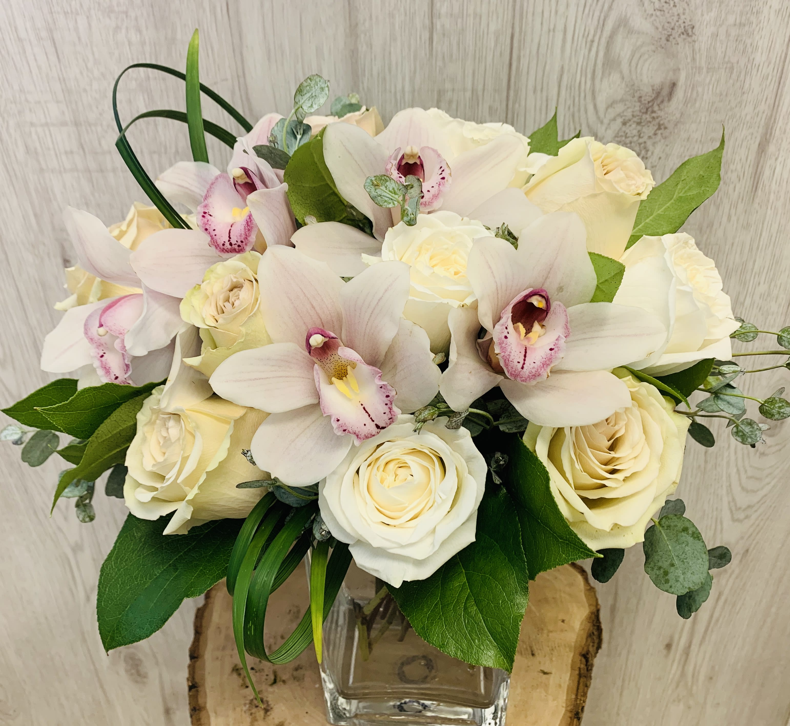 Scottsdale Beauty  - White roses and orchids in a beautiful romantic arrangement.  Upgrades include more flowers and larger vase for a fuller arrangement.   low compact arrangement. 