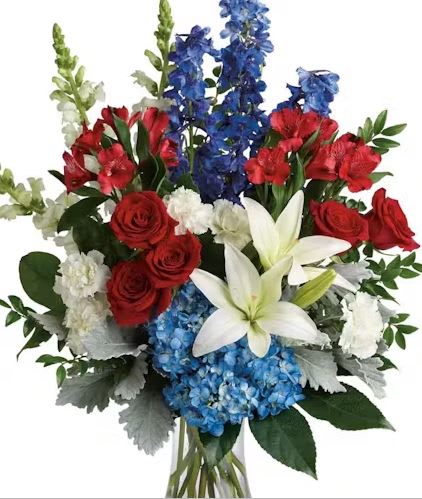 PATRIOTIC VASE ARRANGEMENT - This beautiful array of patriotic colored flowers show your respect and honor. The fresh flowers are designed in a stunning fan-style vase design, with minimal greenery.  We bring all the beauty together with premium Roses, blue Delphinium, and bold, white Chrysanthemums. Accents of Snapdragons, Carnations, Daisies, and Hydrangea make this one of our most desired celebration designs.  Displays wonderfully on a buffet table, kitchen island, or side table.  *** VASE WILL VARY****
