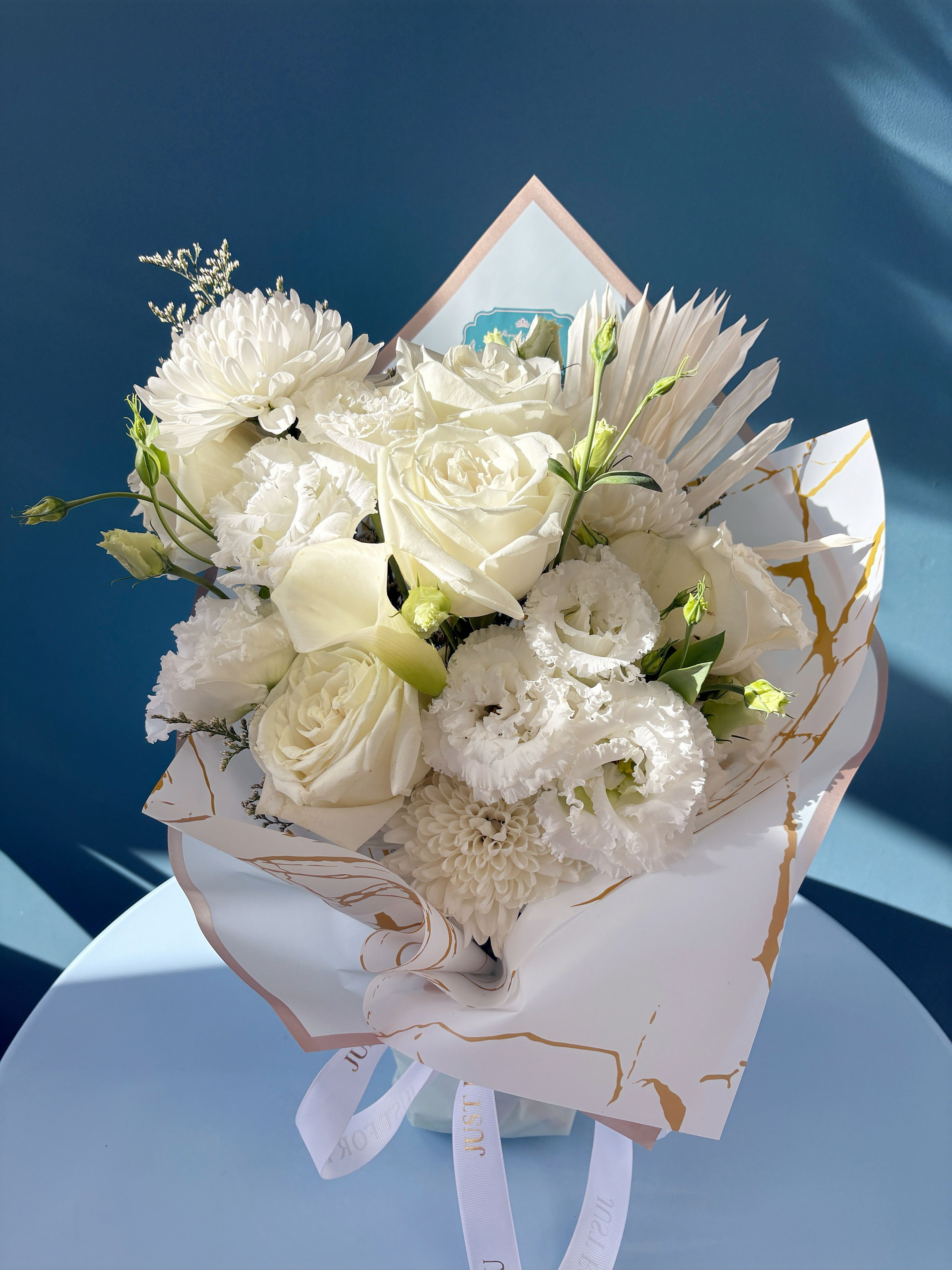 White bouquet with roses, chrysanthemums, and lisianthus in decorative wrap