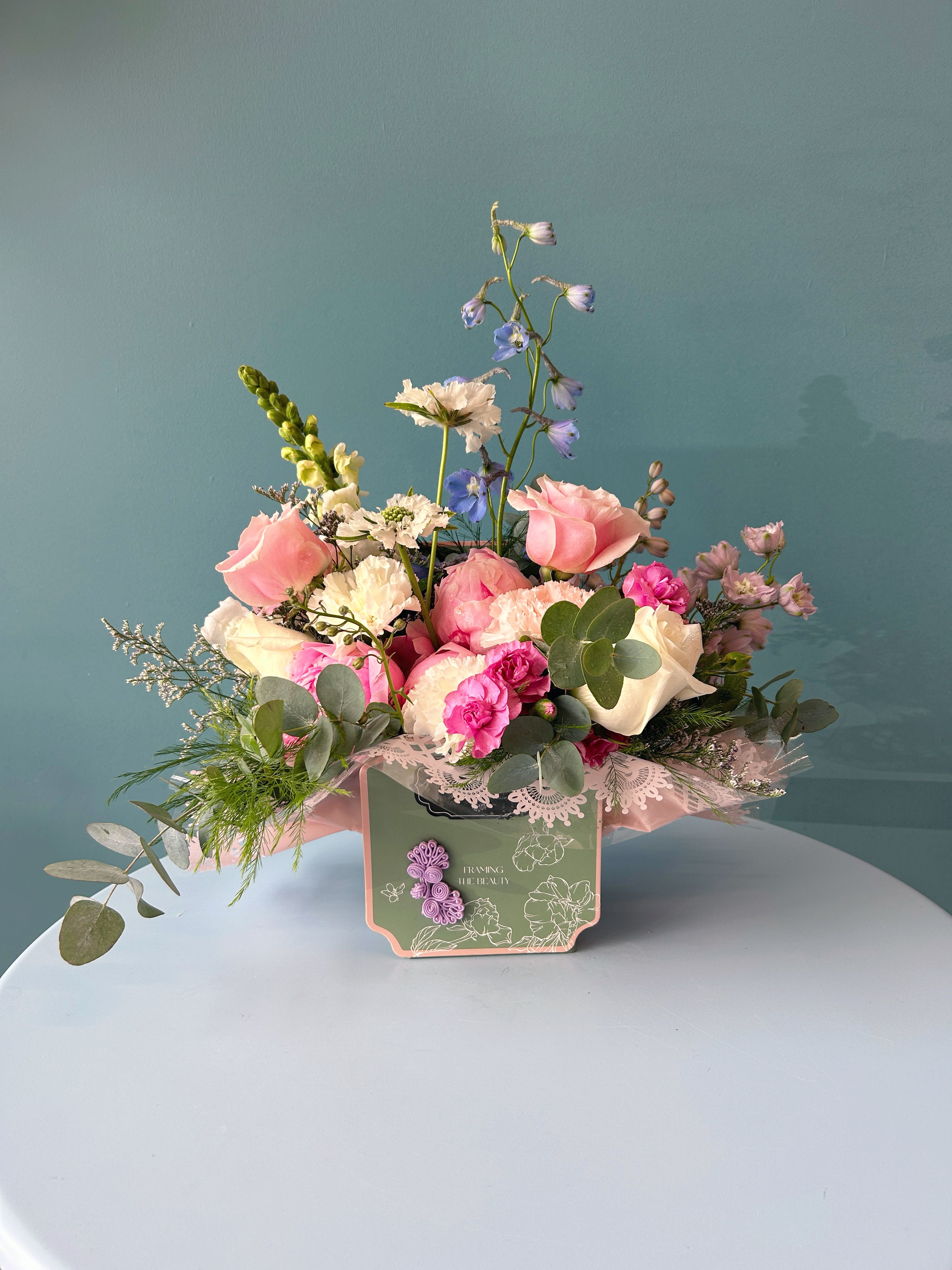 Pink and white mixed flower arrangement in a decorative box