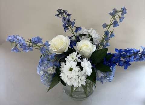 Sapphire Skies - Sapphire Skies is a timeless arrangement featuring vibrant blue delphinium, lush blue hydrangeas, elegant white roses, and cheerful white daisies. Designed with a fresh blue-and-white color palette, this bouquet brings a sense of serenity and sophistication, making it a beautiful choice for birthdays, anniversaries, sympathy, celebrations, or simply brightening someone's day.