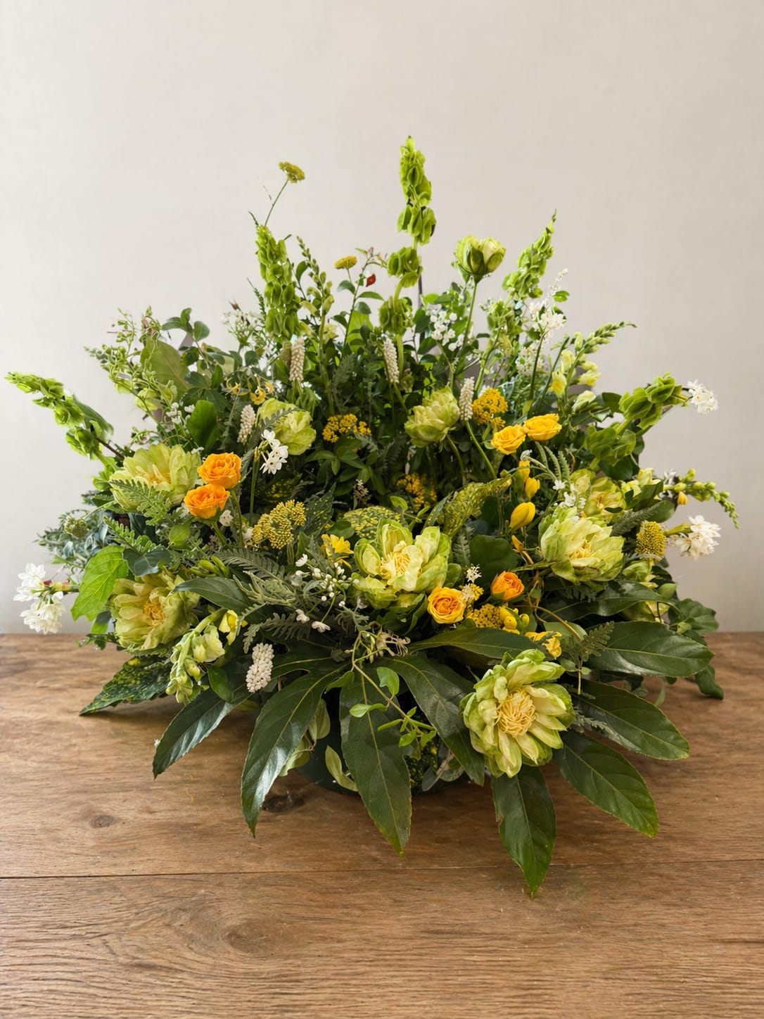 English Elegance Cremation Wreath - A dignified, textured tribute created to honor a beautiful legacy. Originally designed in memory of Mr. AC English, this premium arrangement features striking Bells of Ireland, lush yellow and green "veggie" cabbage roses, cushion mums, and delicate accent blooms.   This piece can be fully customized with your preferred color palette or flower types—please contact the shop directly for specific custom requests.