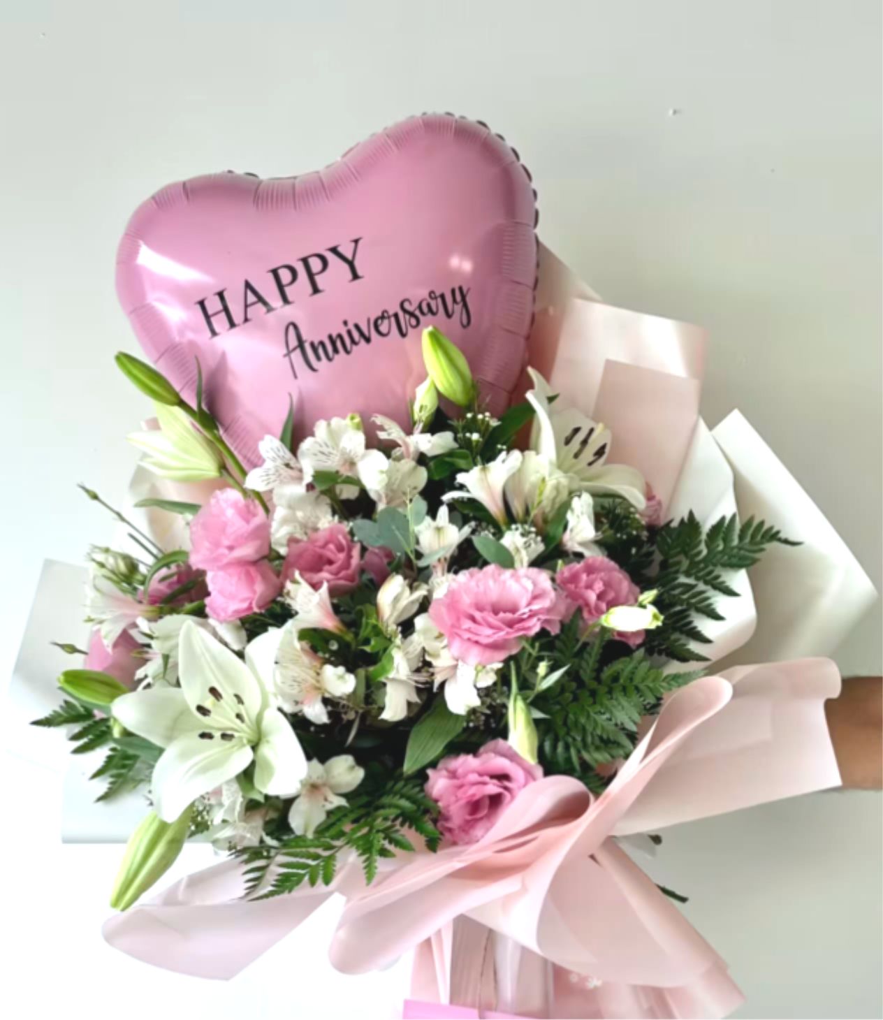 Pink heart balloon above a bouquet of pink and white flowers