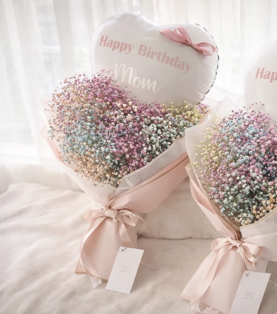 Two pastel baby’s breath bouquets with pink ribbons and birthday balloons