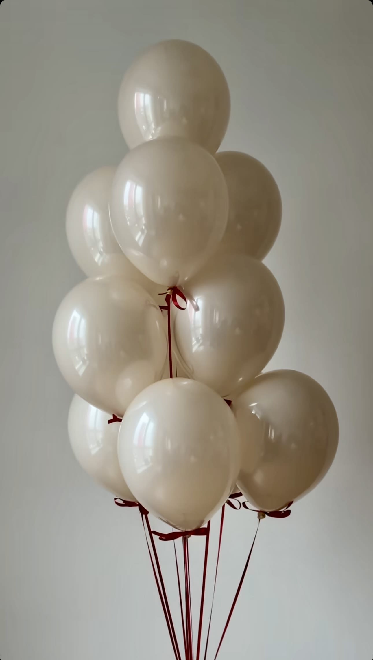 Cluster of cream-colored balloons tied with red ribbons