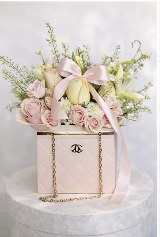 Pink and white flowers arranged in a pale pink box with a ribbon bow