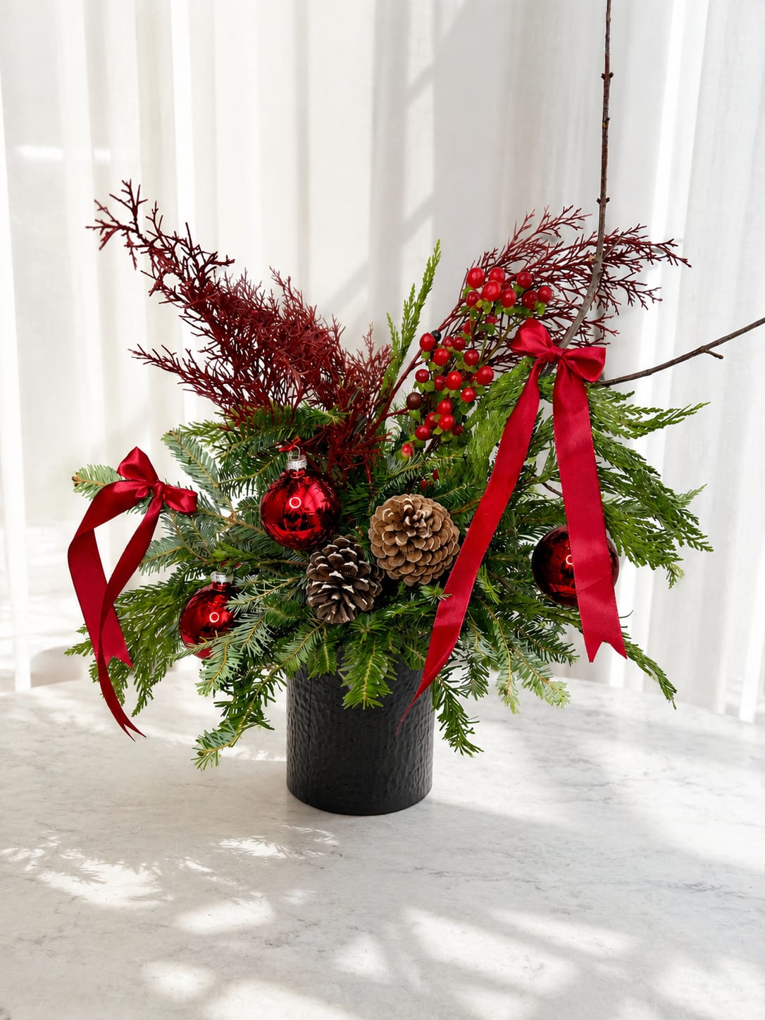 Christmas  Gift Arrangement - Celebrate the holiday season with our Holiday Evergreen Floral Arrangement, a luxurious Christmas greenery design made with fresh seasonal evergreens, pine branches, natural pinecones, festive red ornaments, winter berries, and elegant red satin ribbons.  This handcrafted Christmas floral arrangement is beautifully designed in a modern black container and makes the perfect holiday gift box, Christmas centerpiece, or festive home décor piece. Ideal for gifting, hosting, or adding warmth and elegance to any space during the holidays.  Each arrangement is made fresh to order using premium holiday greenery, ensuring a unique and high-quality seasonal design.  christmas flowers in myrtle beach