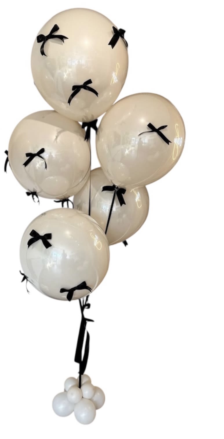 Cluster of cream balloons with black bows and a black ribbon tail