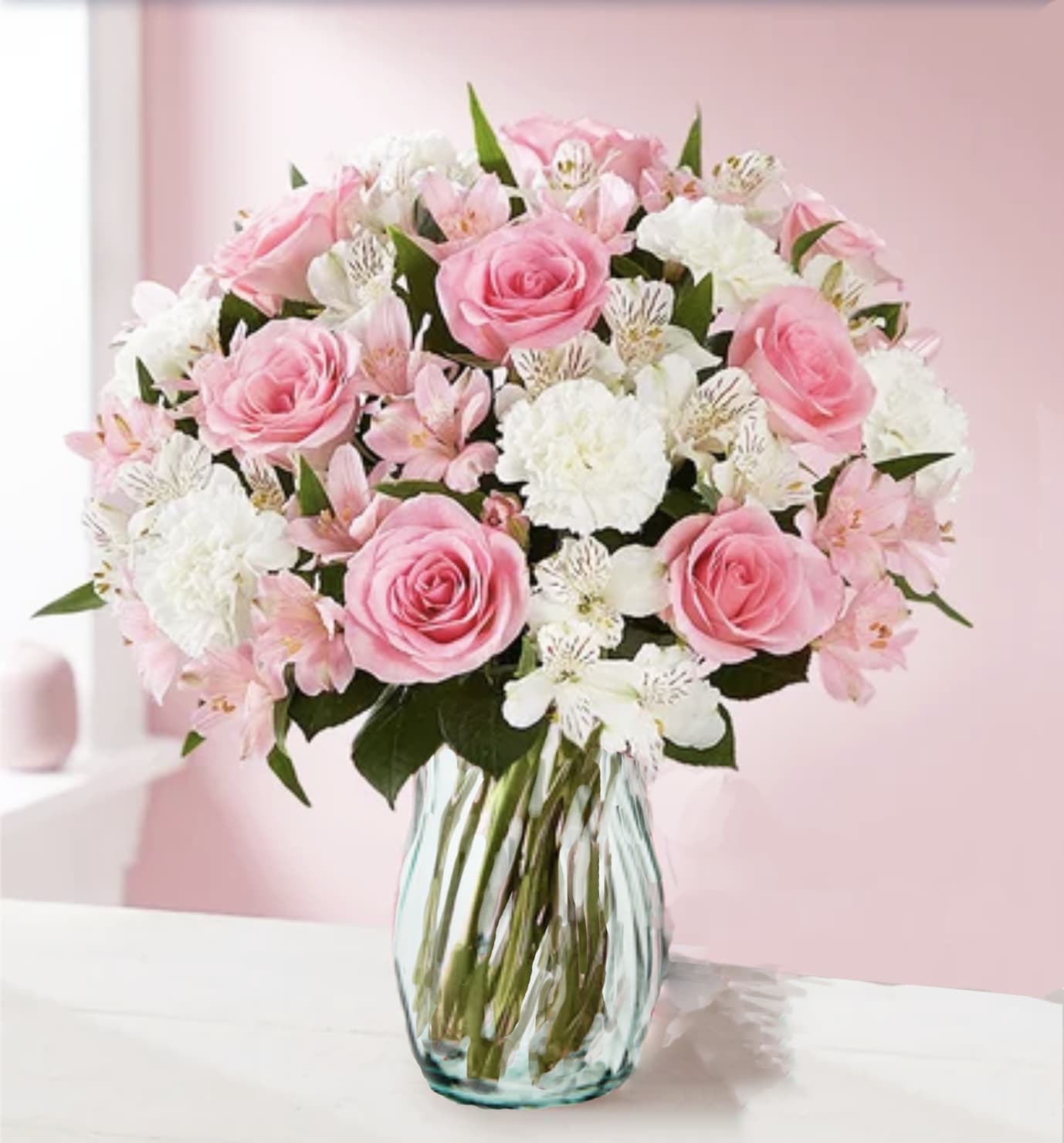 Pink roses and white flowers arranged in a clear glass vase
