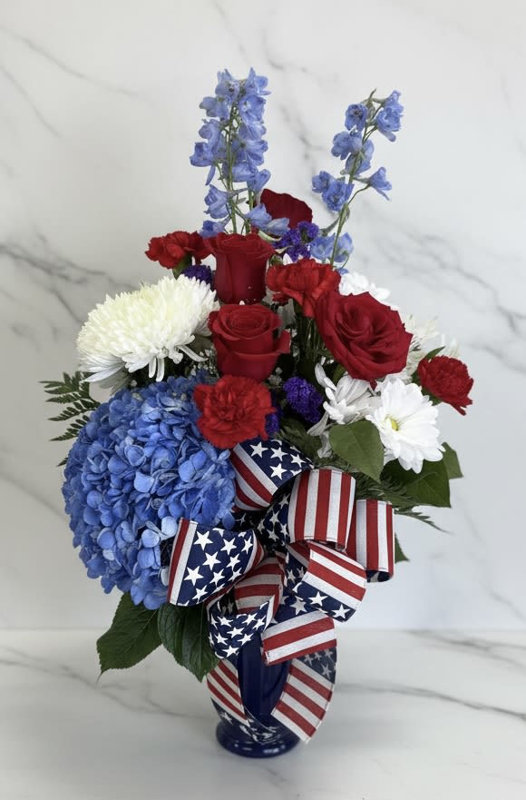 AMERICA 250!! - Celebrate America with our own  patriotic AMERICA 250 arrangement: blue hydrangea, red roses, white daisies &amp; carnations in blue vase with festive flag ribbon.  