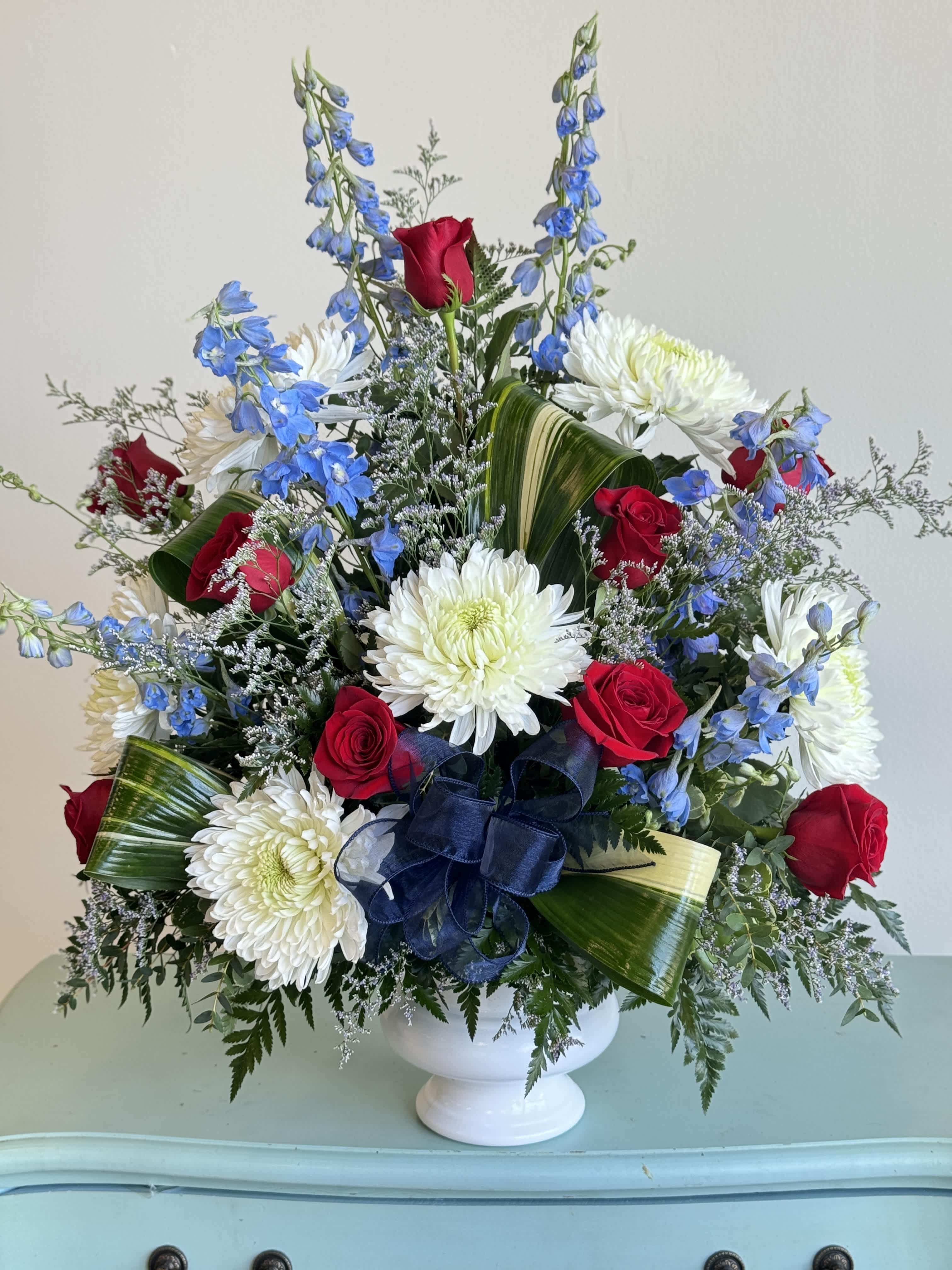 Red roses and white chrysanthemums in a white vase with blue flowers