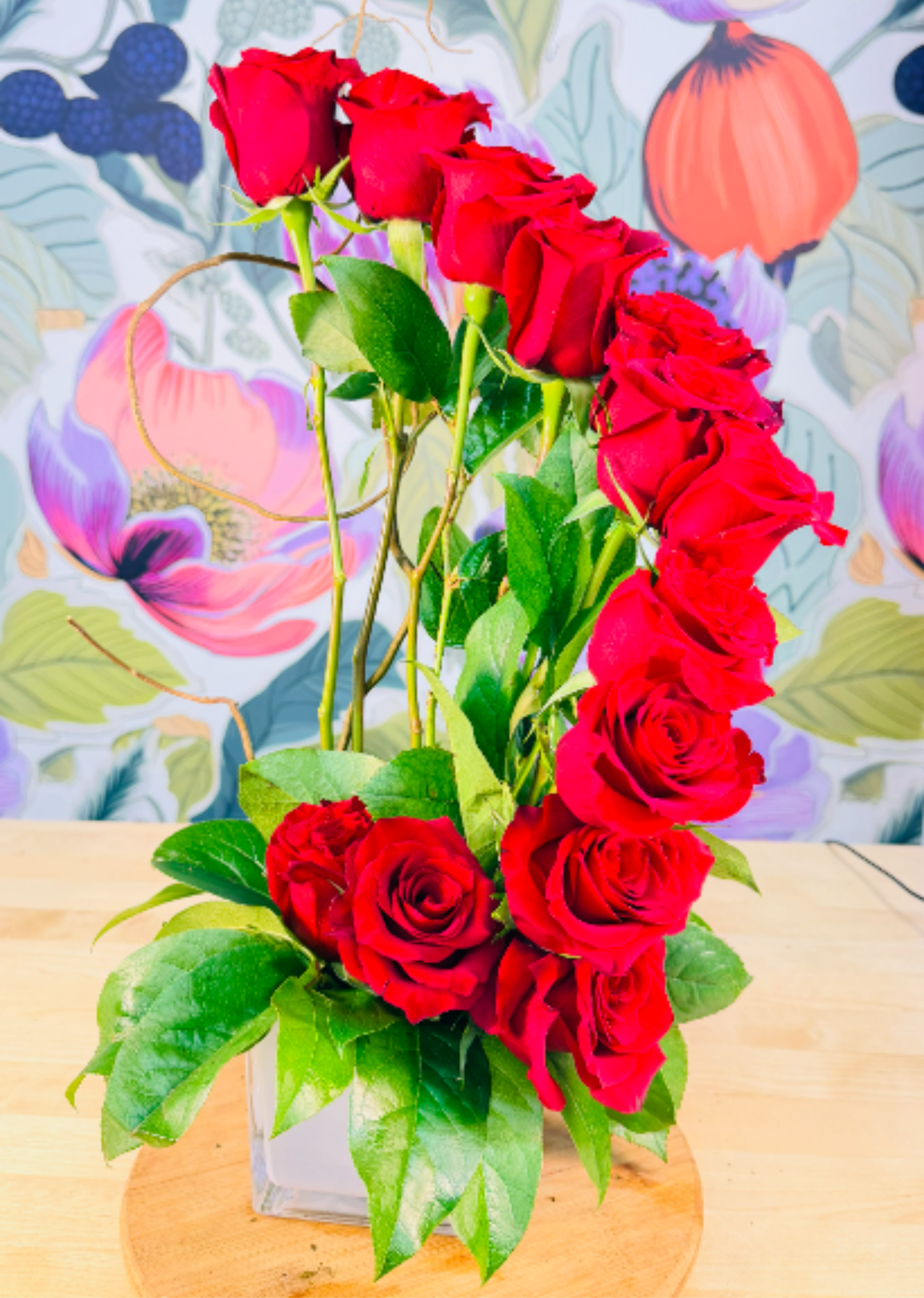 Crimson Crescendo  - A dramatic column of vivid red roses draws the eye upward in this romantic flower arrangement-perfect as a birthday bouquet, anniversary roses, or an everyday expression of love. The tall, upright silhouette and loose vertical cascade give the person you're sending it to a feeling of classic elegance and celebration, while the strong red-and-green contrast reads timelessly romantic.