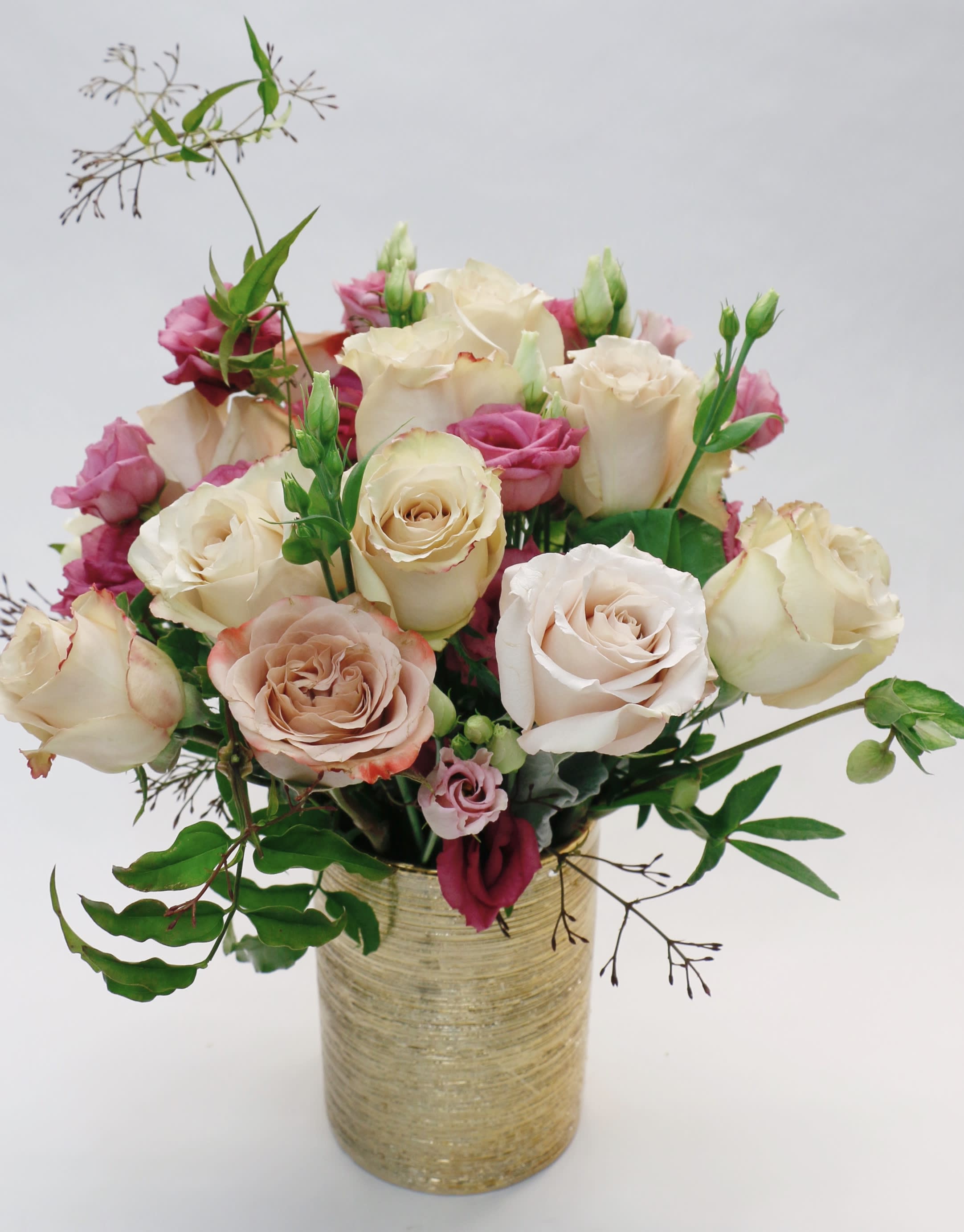 Bouquet of cream and pink roses in a gold vase