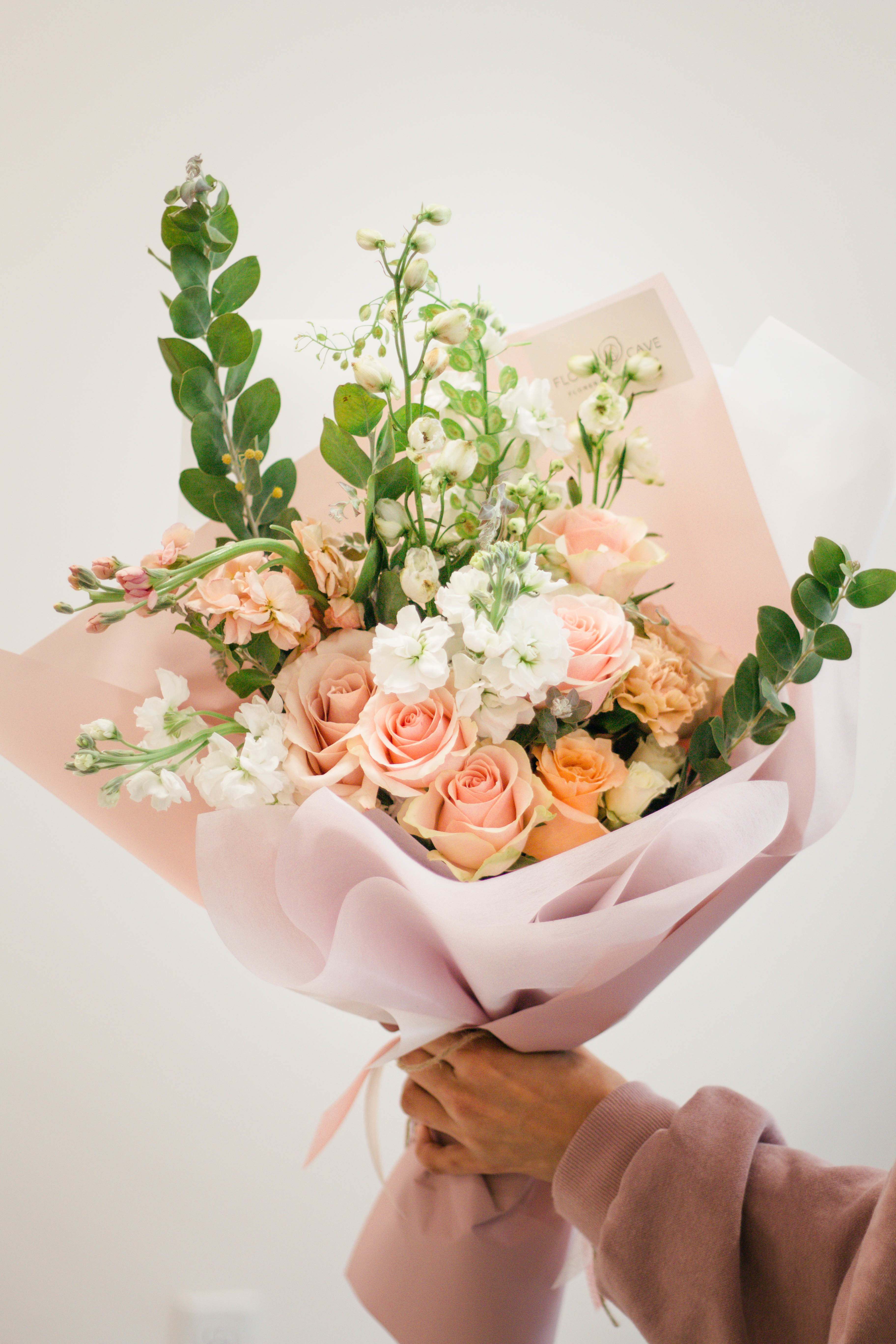 Handheld bouquet of peach and white roses with airy white blooms