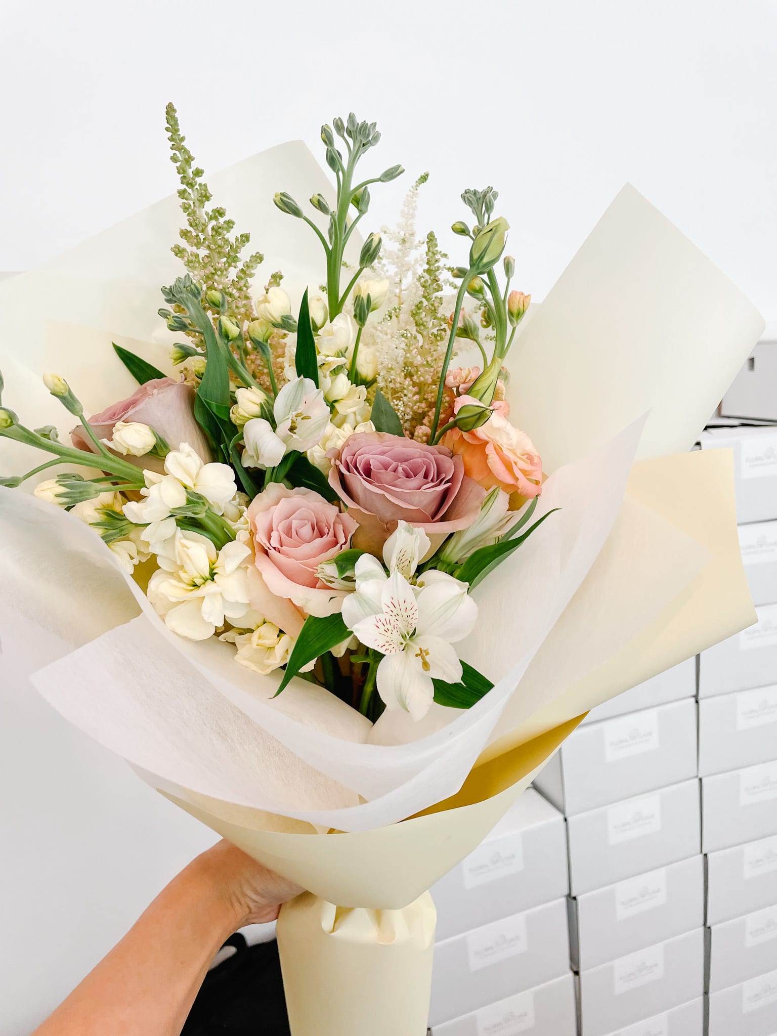 Bouquet of pink roses and white flowers wrapped in cream paper