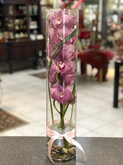 Tall glass cylinder with pink orchids and a pink ribbon