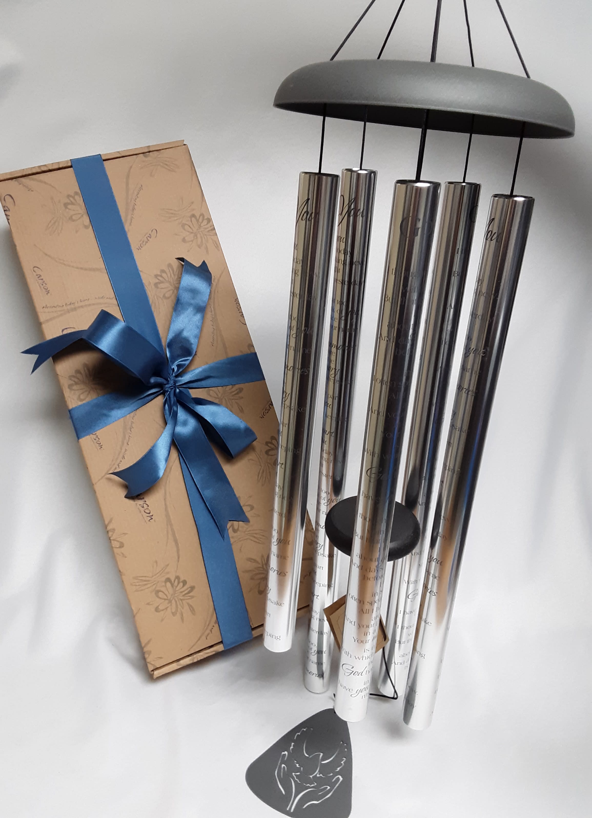 Gift box with blue ribbon beside a set of silver wind chimes