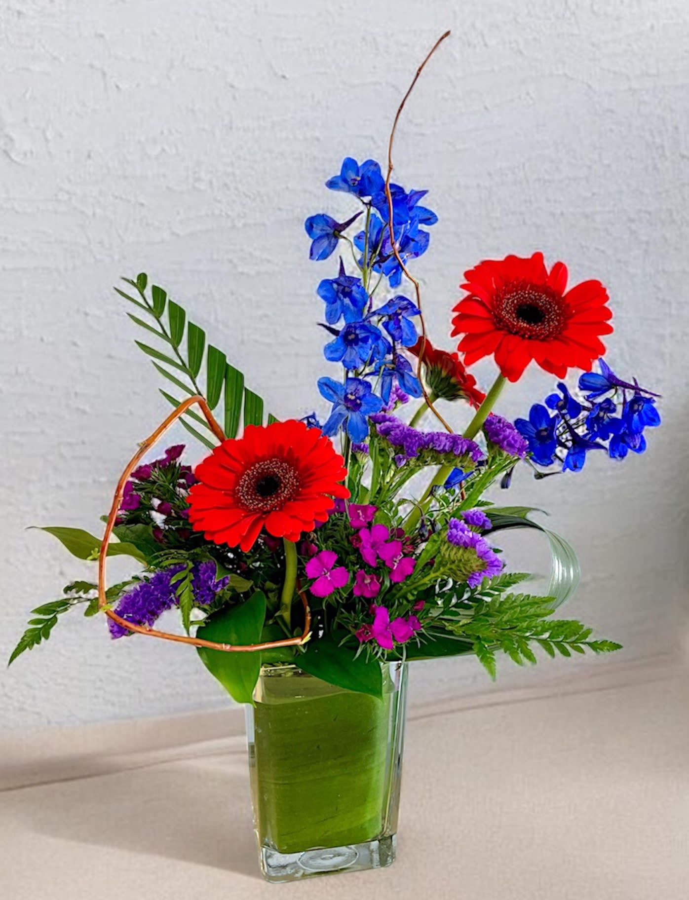 Lively - The airy, asymmetrical silhouette and playful color mix, red, blue, purple, and fresh green-feel energetic and celebratory, the kind of arrangement that makes the person you're thinking of smile the moment they see it. Great for a bright birthday, get well or cheerful thinking of you gift. 