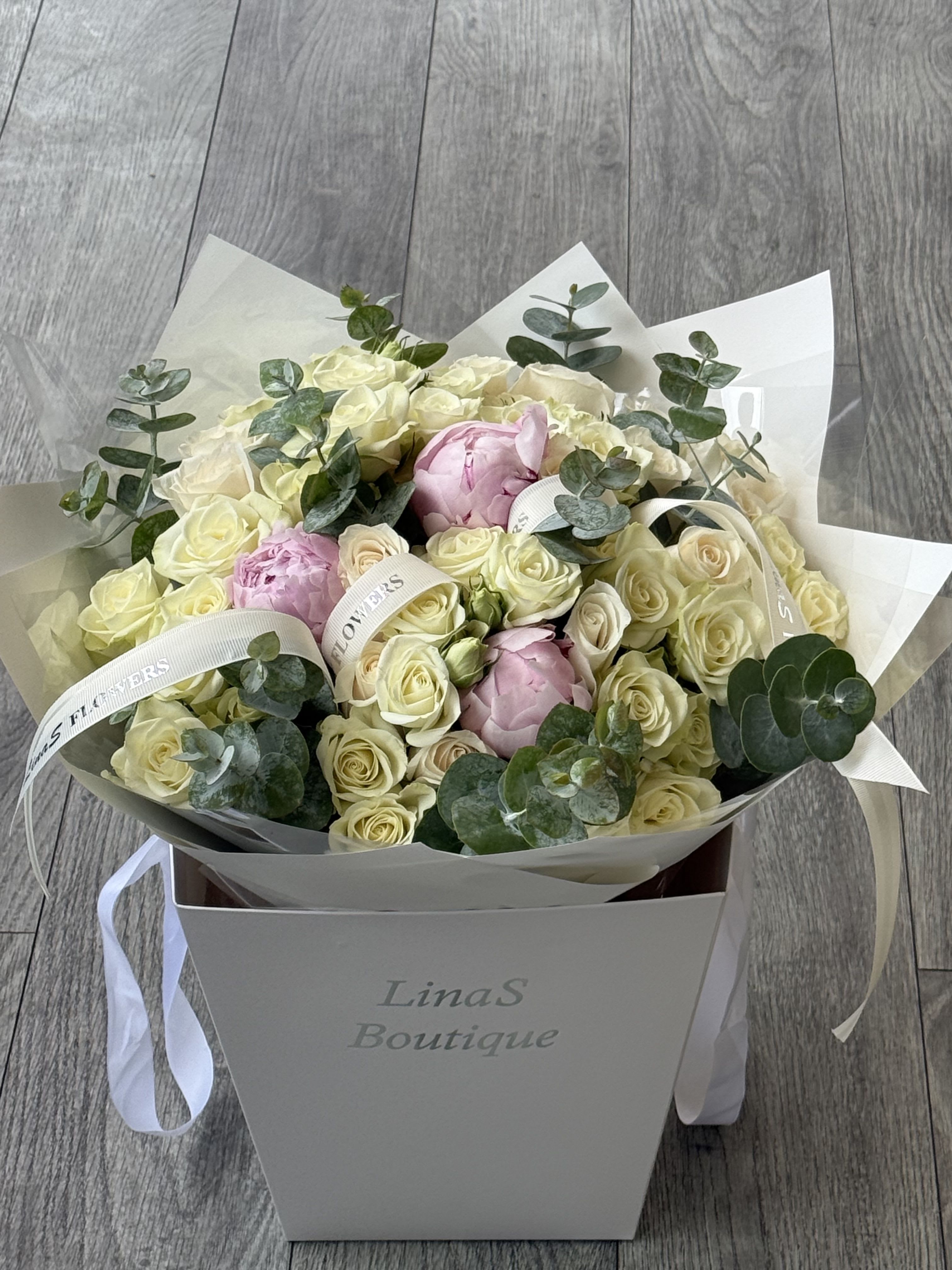 Dream - A charming bouquet featuring a blend of classic roses, delicate spray roses, and lush peonies creates an elegant and romantic arrangement. The roses provide timeless beauty, the spray roses add a touch of whimsy, and the peonies offer a soft, full texture, all harmonizing in a captivating display of color and fragrance.