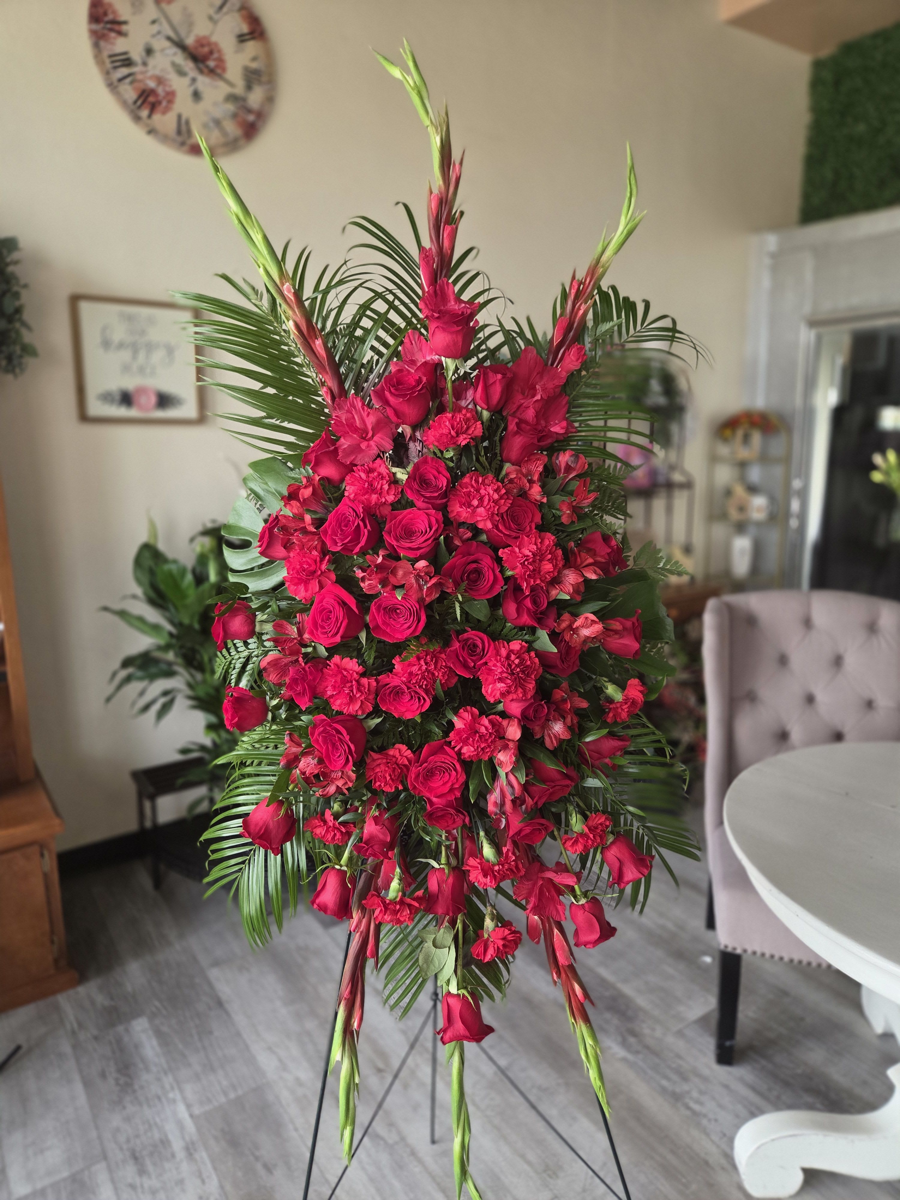 Forever Feelings by BloomNation™ - Red is the color of love and this standing spray displays it with luxurious style. Red roses and palms come together with other red and greenery to create a beautiful salute.