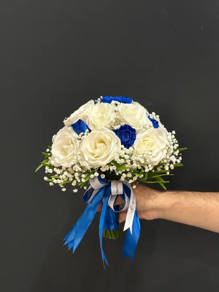 Handheld bouquet of white and blue roses with ribbon