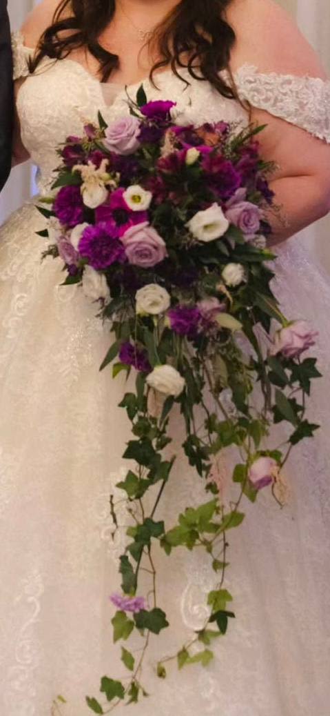 Bride holding a cascading bouquet of purple, lavender, and white flowers