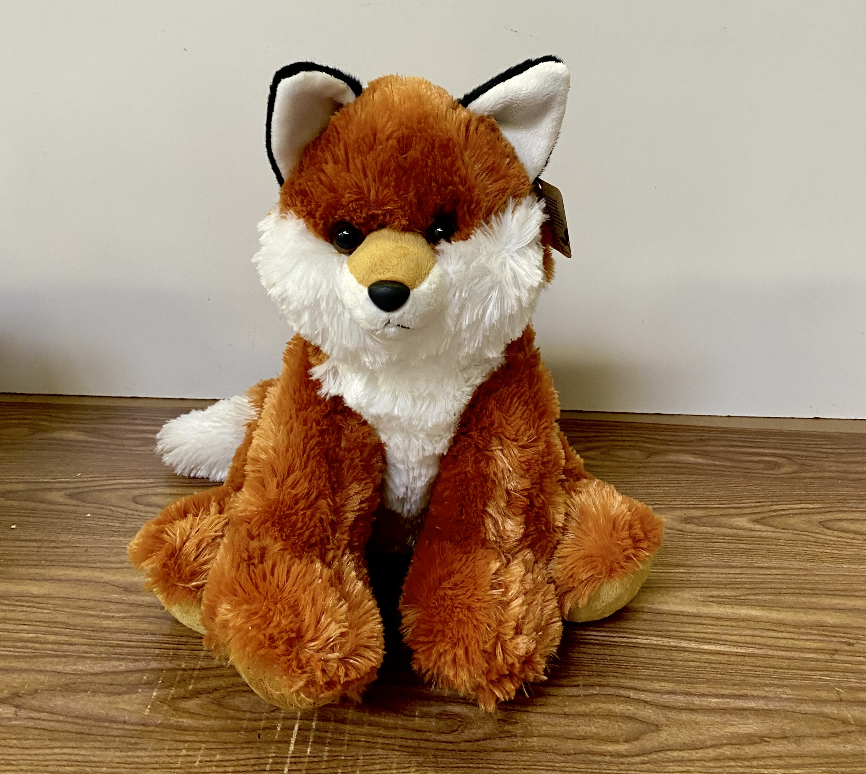 Plush fox toy sitting on a wooden floor