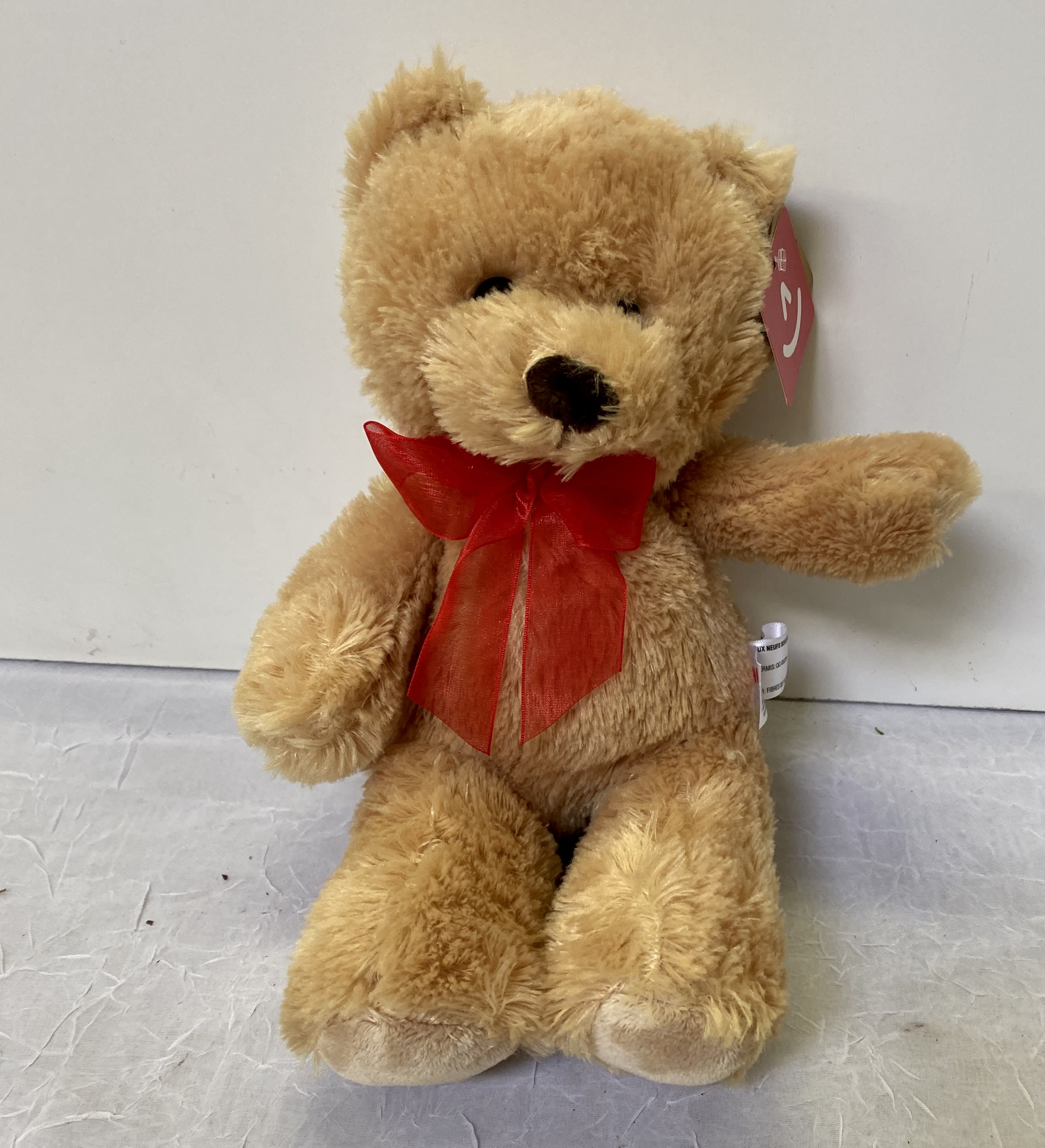 Tan teddy bear with a red ribbon bow