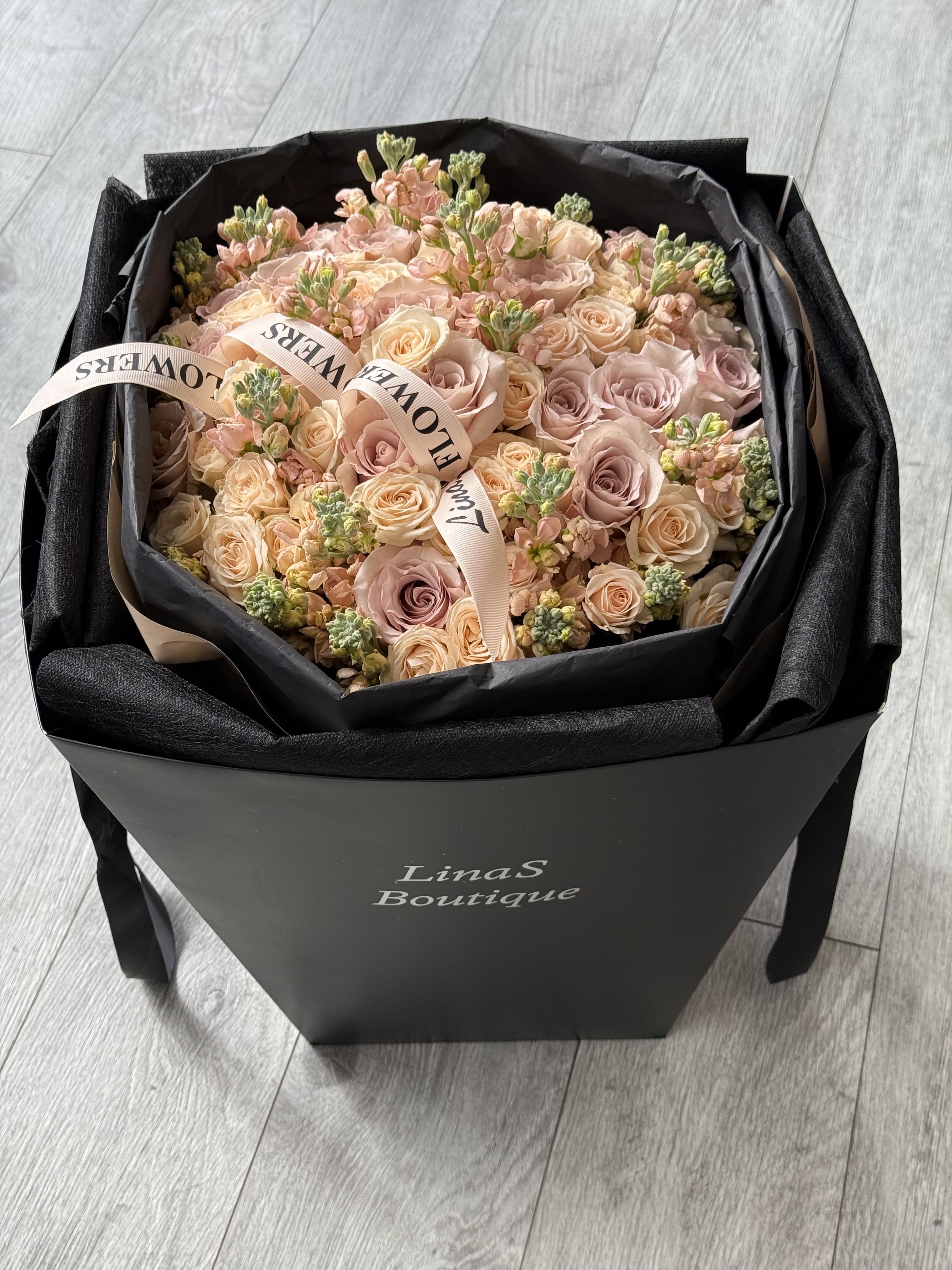 Bouquet of blush and peach roses in a black gift box