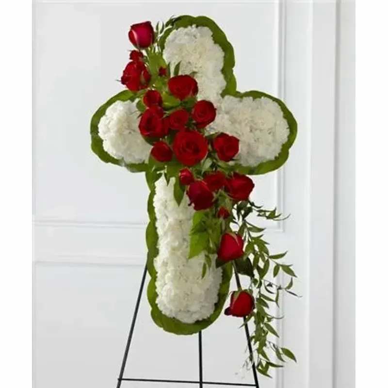 FTD Floral Cross Easel - White carnations are arranged to form a cross in which an accent of red roses, spray roses, and lush greens are draped across the center, creating a beautiful display of serene elegance. Displayed on a wire easel. 