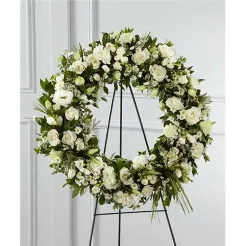 FTD Splendor™ Wreath For A Child Small - Elegant white freesia, double lisianthus, spray roses, monte casino asters and limonium are accented with a variety of lush greens and green raffia ribbon, perfectly arranged in the form of a wreath, to create a beautiful way to display your sincere sentiments. 