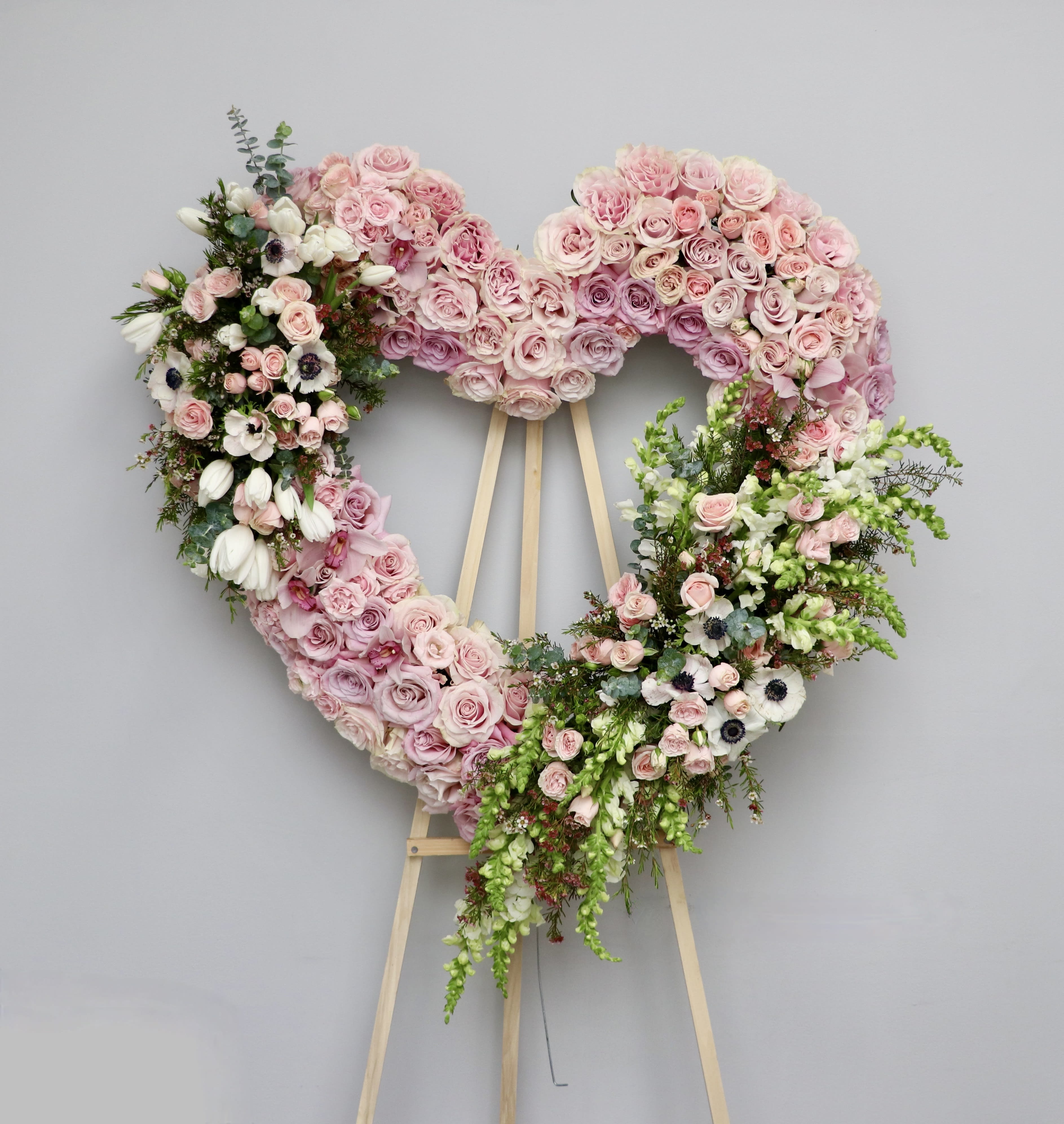Heart's Desire  - Show your love and affection with this stunning arrangement featuring an array of blush pink and white flowers, including anemones, roses, snapdragons, and tulips arranged in a heart shape. This beautiful bouquet will set hearts aflutter.    We include easel, printed banner and delivery (some fees may apply). An additional banner can be added for $15    Standard size is 30'', deluxe is 36'', and premium is 42''.