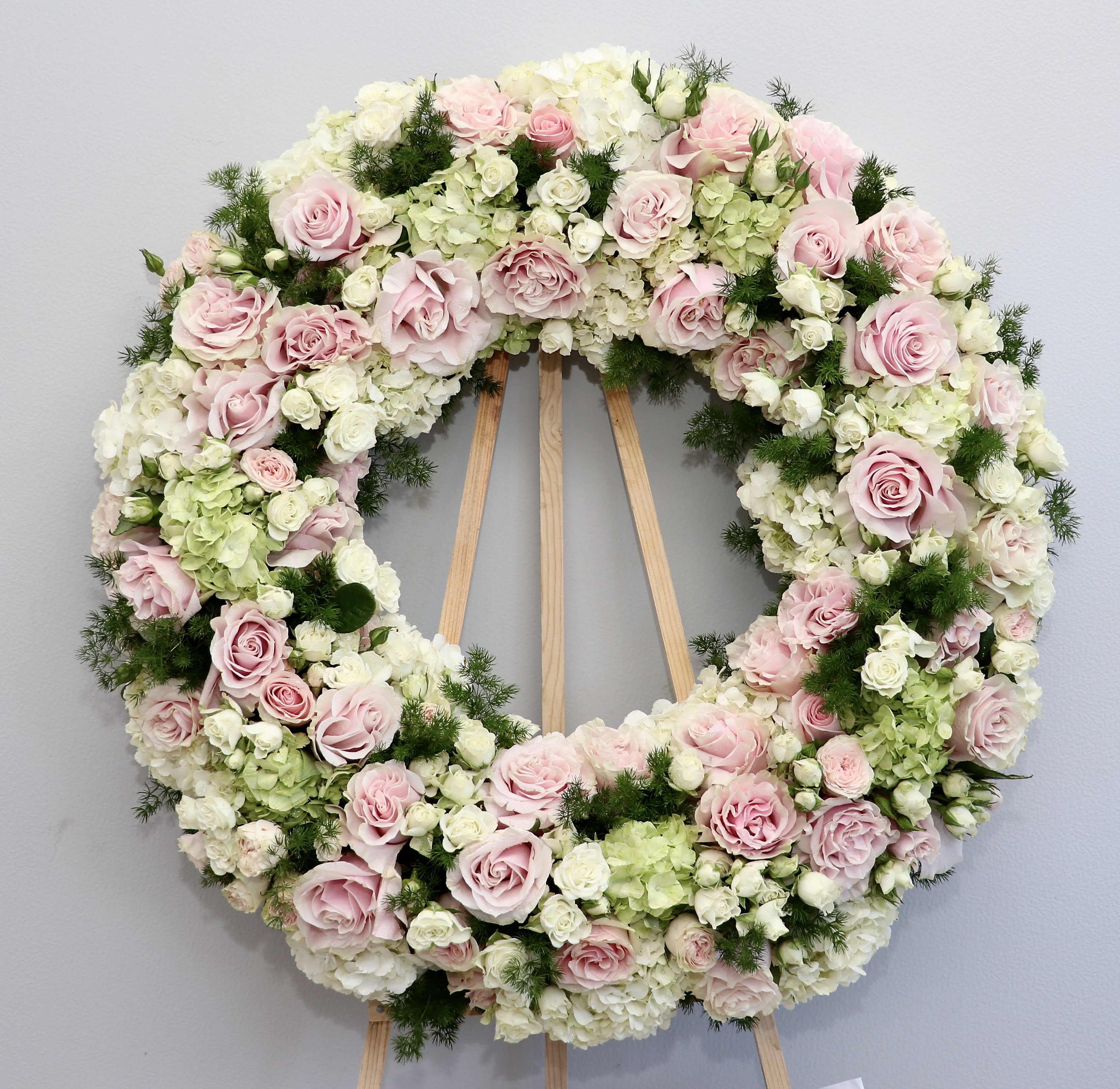 Blush Wreath Wonder  - Blush, white and green seasonal florals make up this gorgeous wreath.    We include easel, printed banner and delivery (some fees may apply). An additional banner can be added for $15    Standard size is 30'', deluxe is 36'', and premium is 42''.