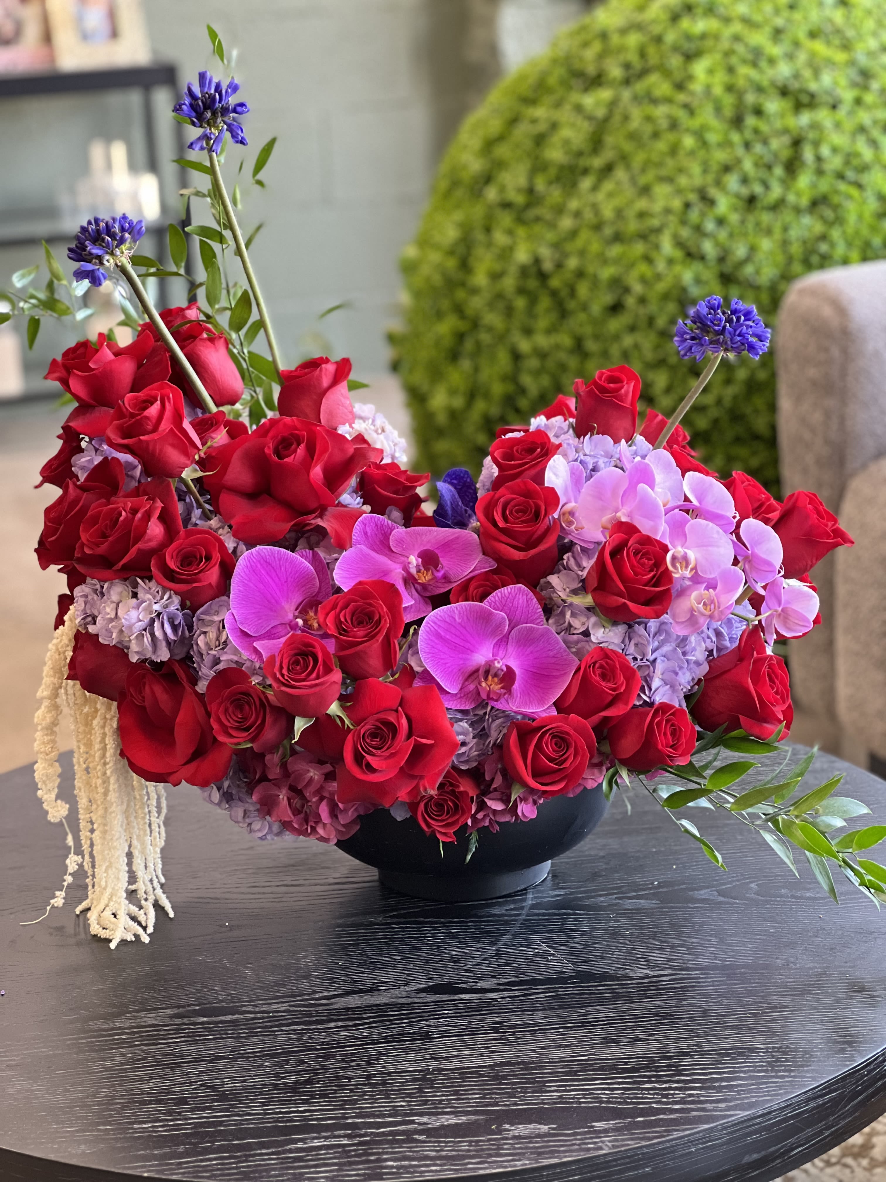 Red roses and pink orchids arranged in a black bowl vase