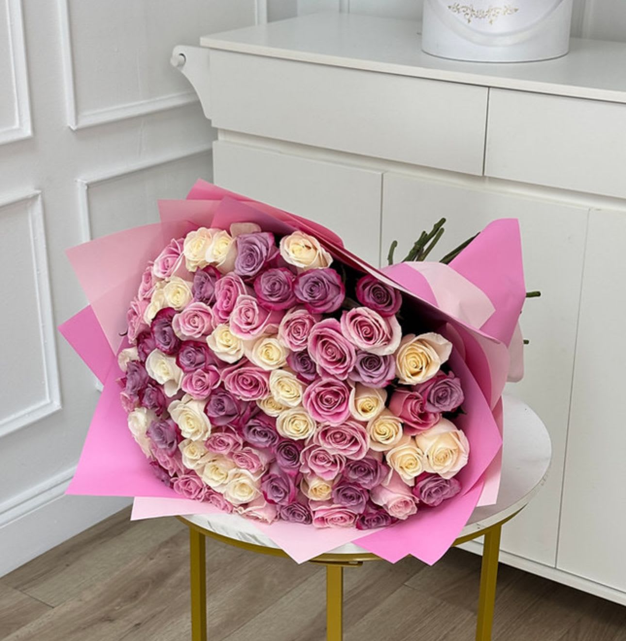 Large bouquet of pink, lavender, and cream roses wrapped in pink paper