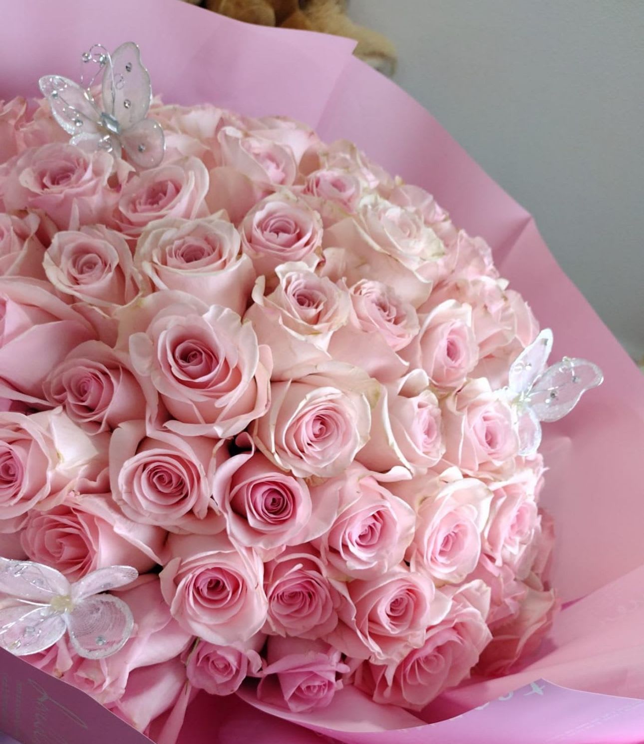 Bouquet of pale pink roses wrapped in pink paper with butterfly picks