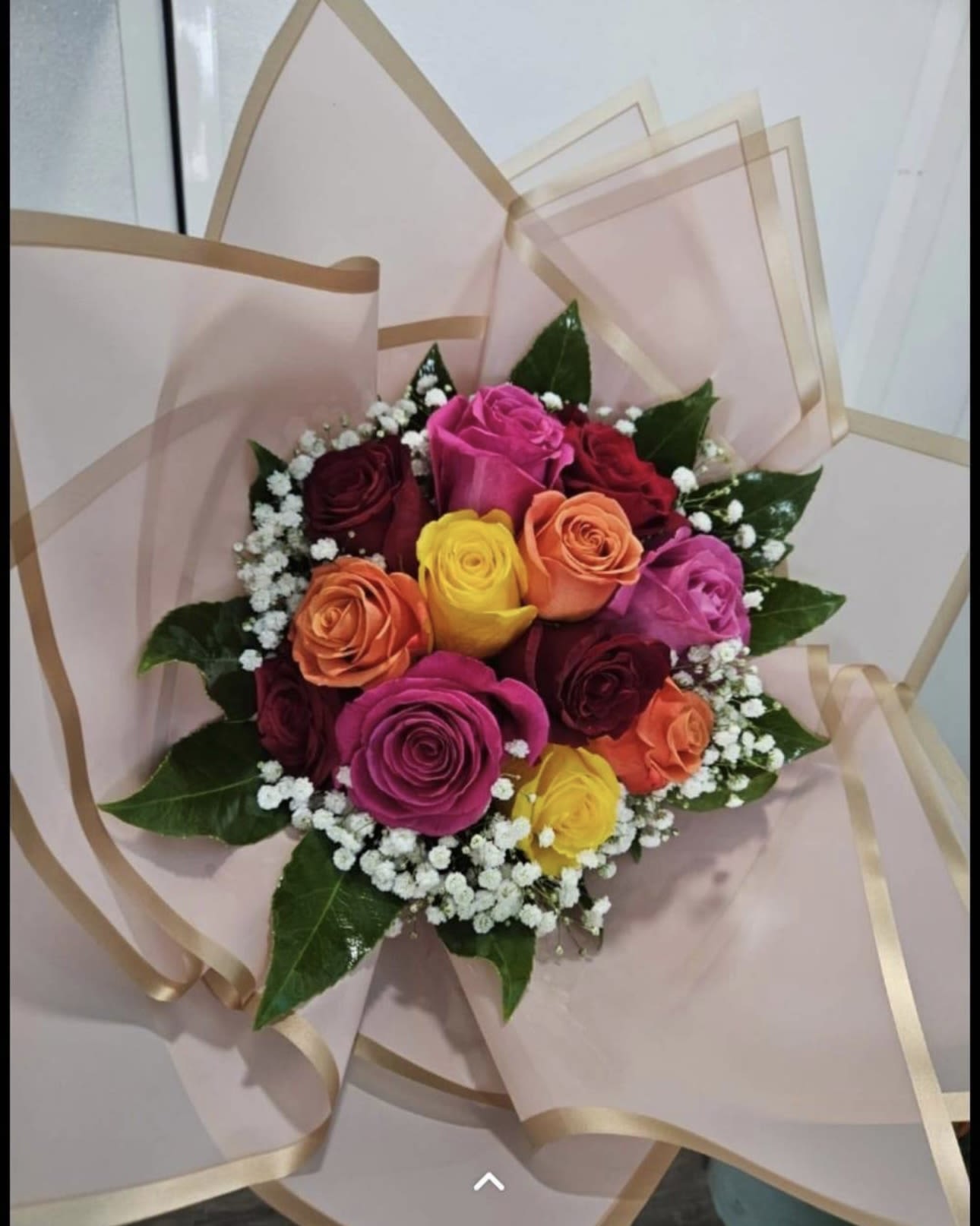 Bouquet of multicolored roses wrapped in pale pink paper