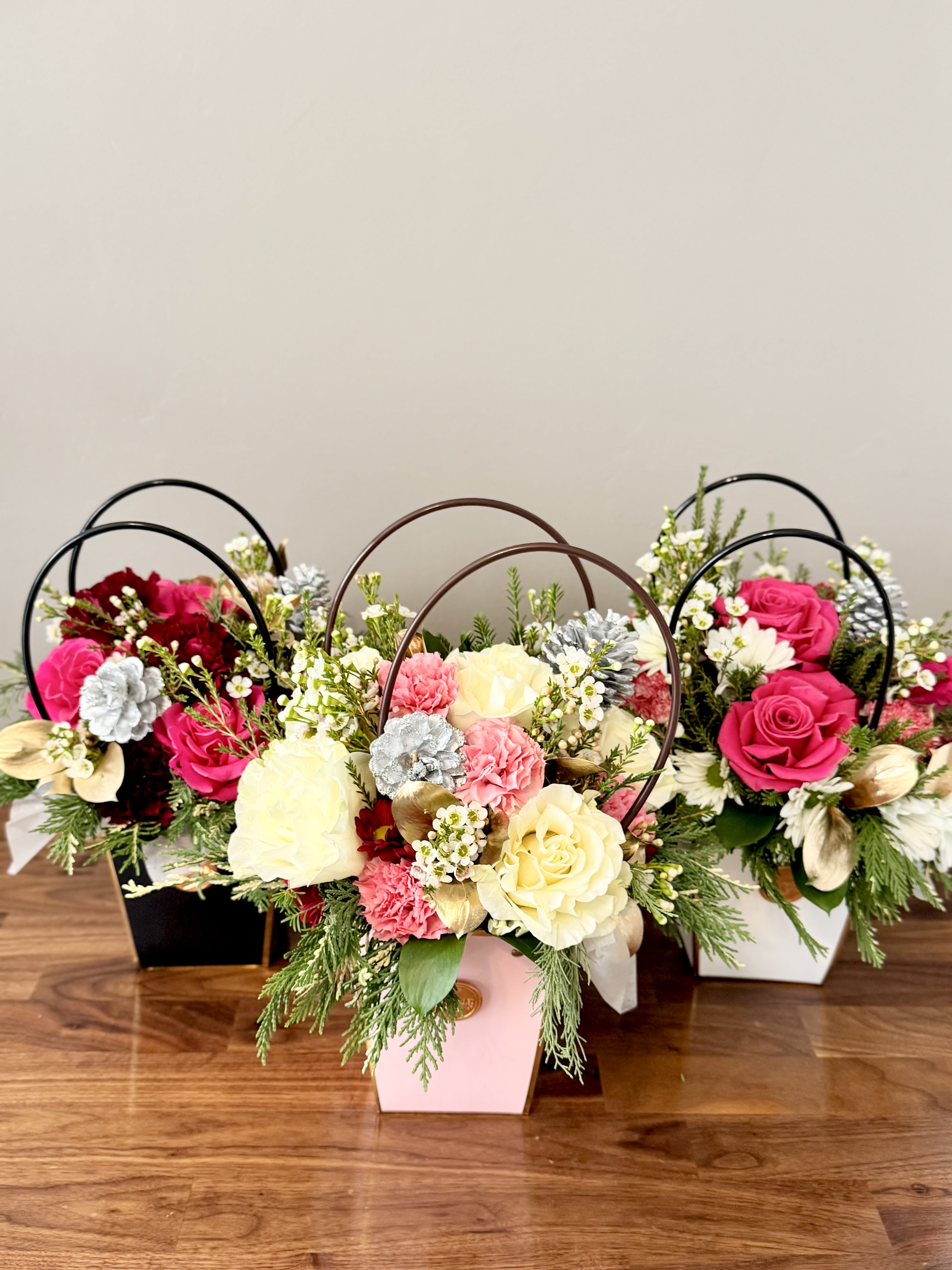 Three floral arrangements in pastel boxes with roses and carnations