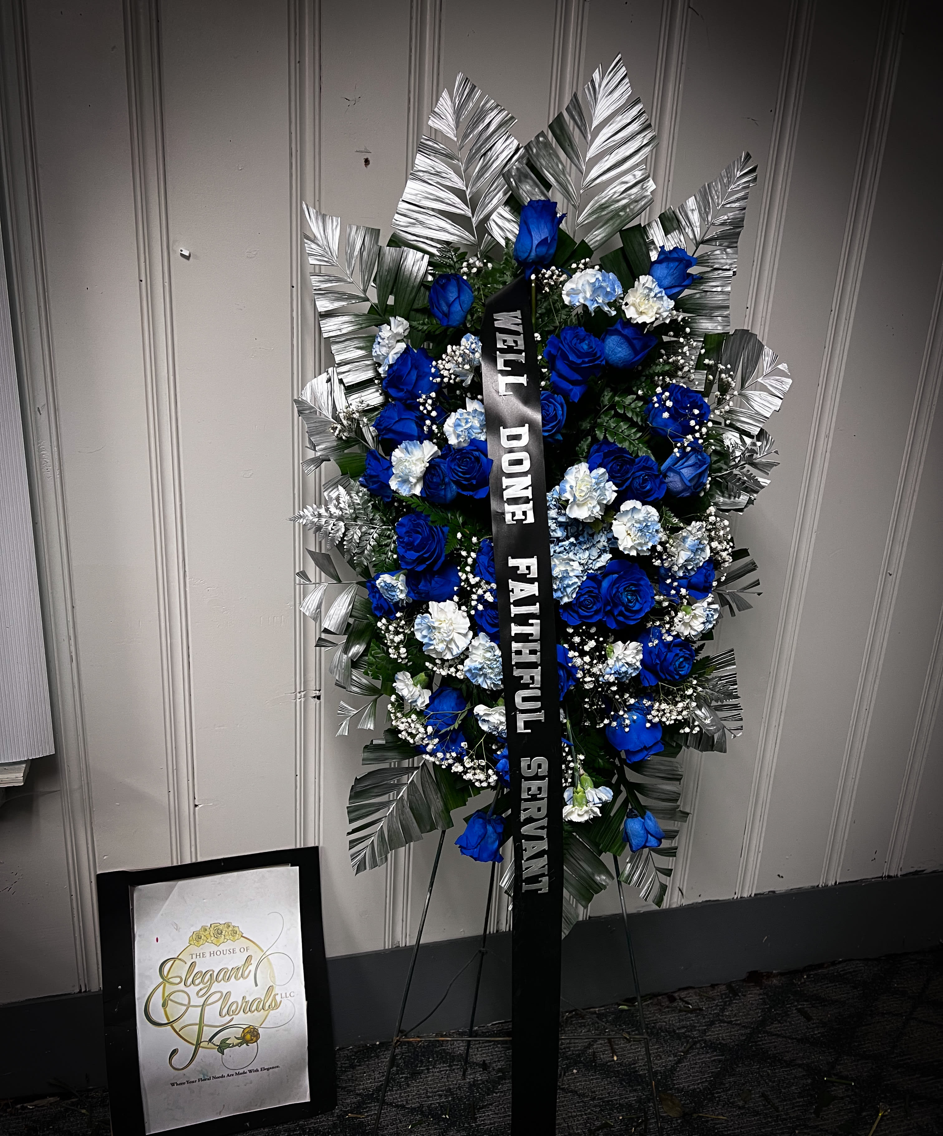 Blue and white funeral standing spray with a black ribbon