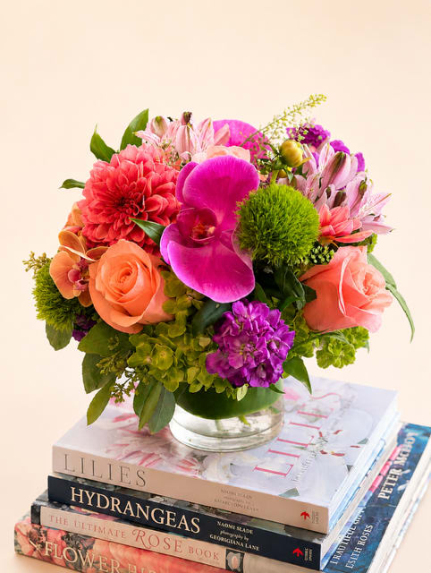 Mixed bouquet of pink, coral, and purple flowers in a glass vase