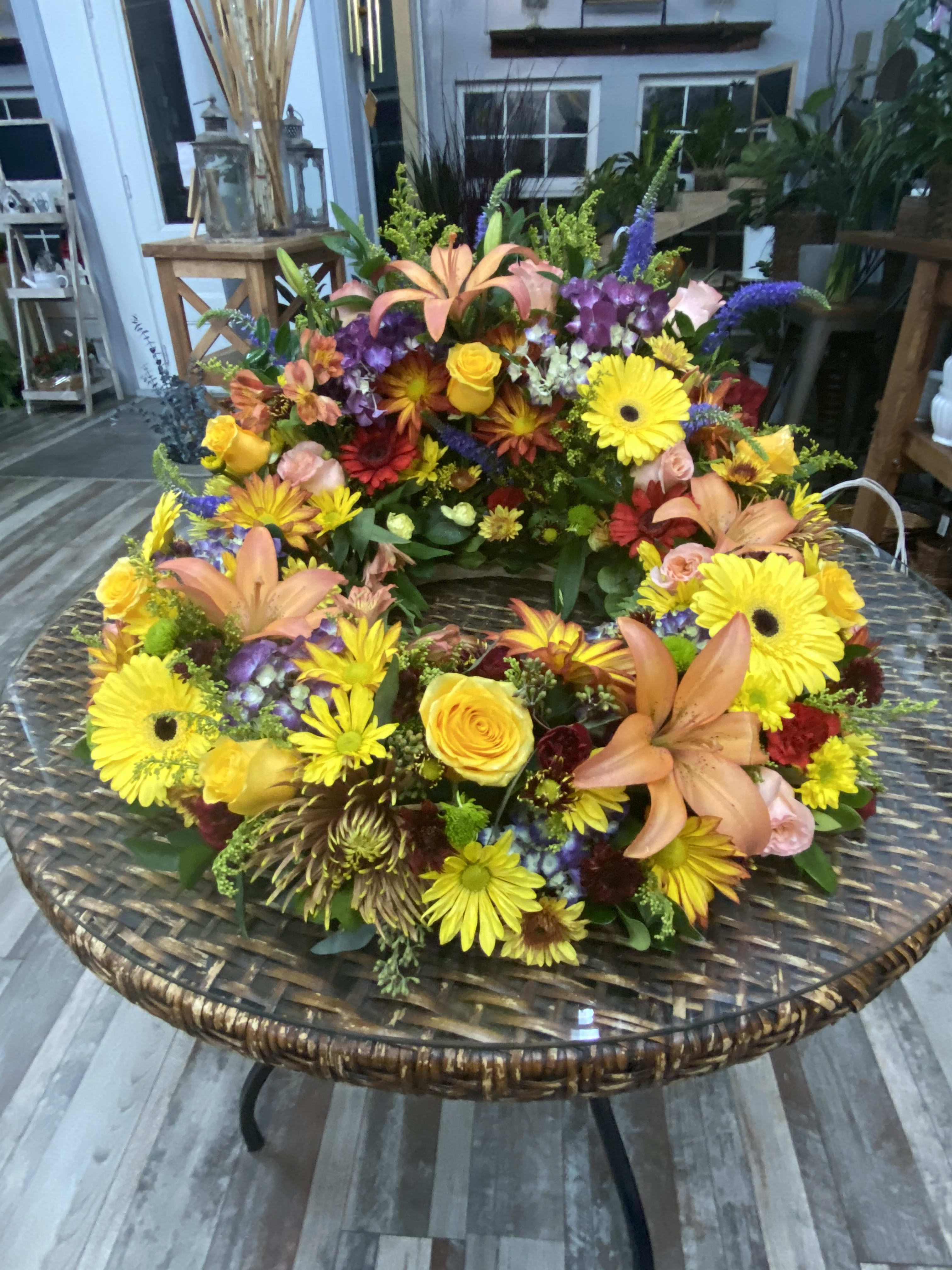 Large colorful floral wreath with lilies, roses, and daisies on a round table