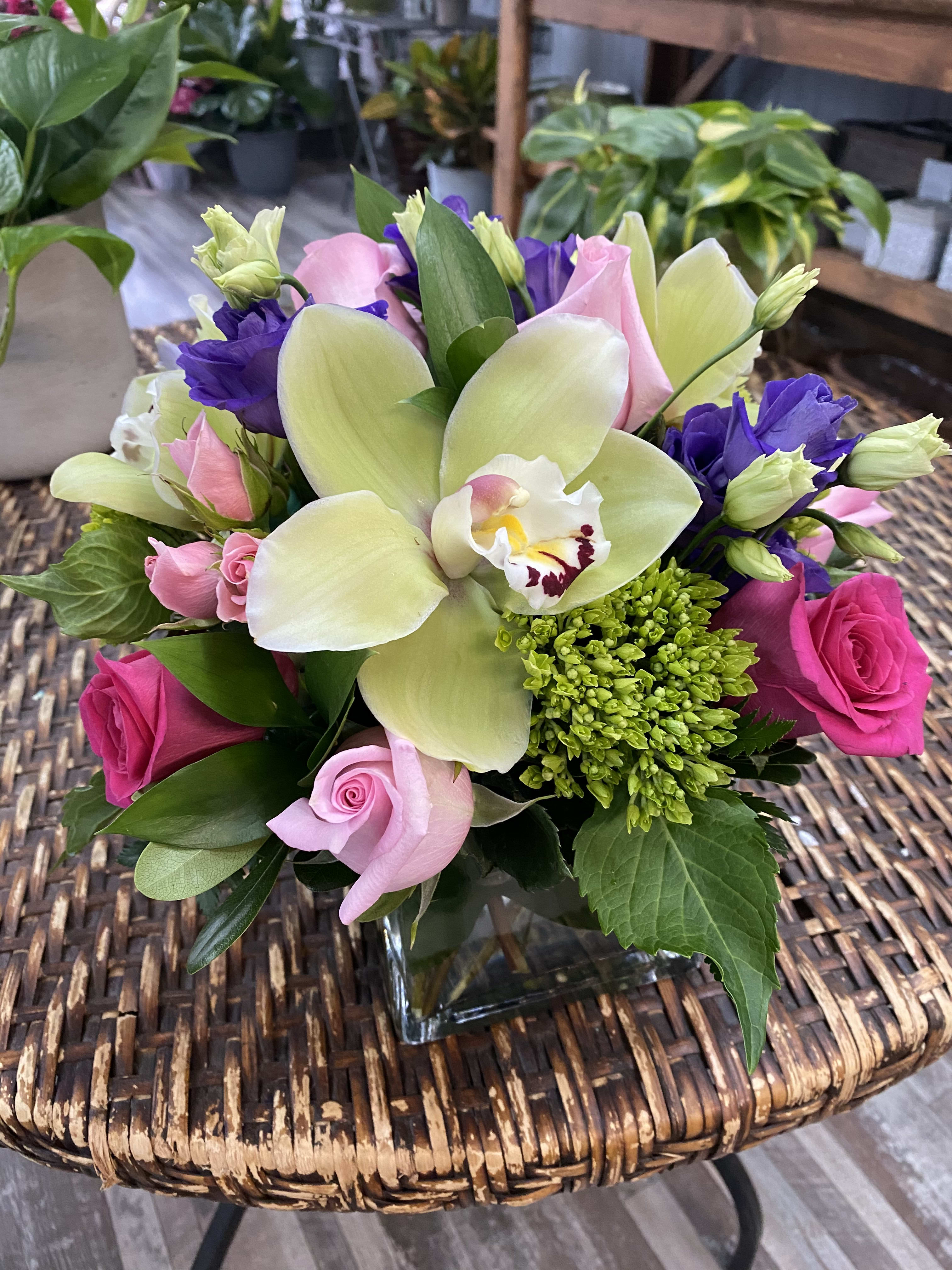 Bouquet of pink roses, purple lisianthus, and a pale orchid in a glass vase